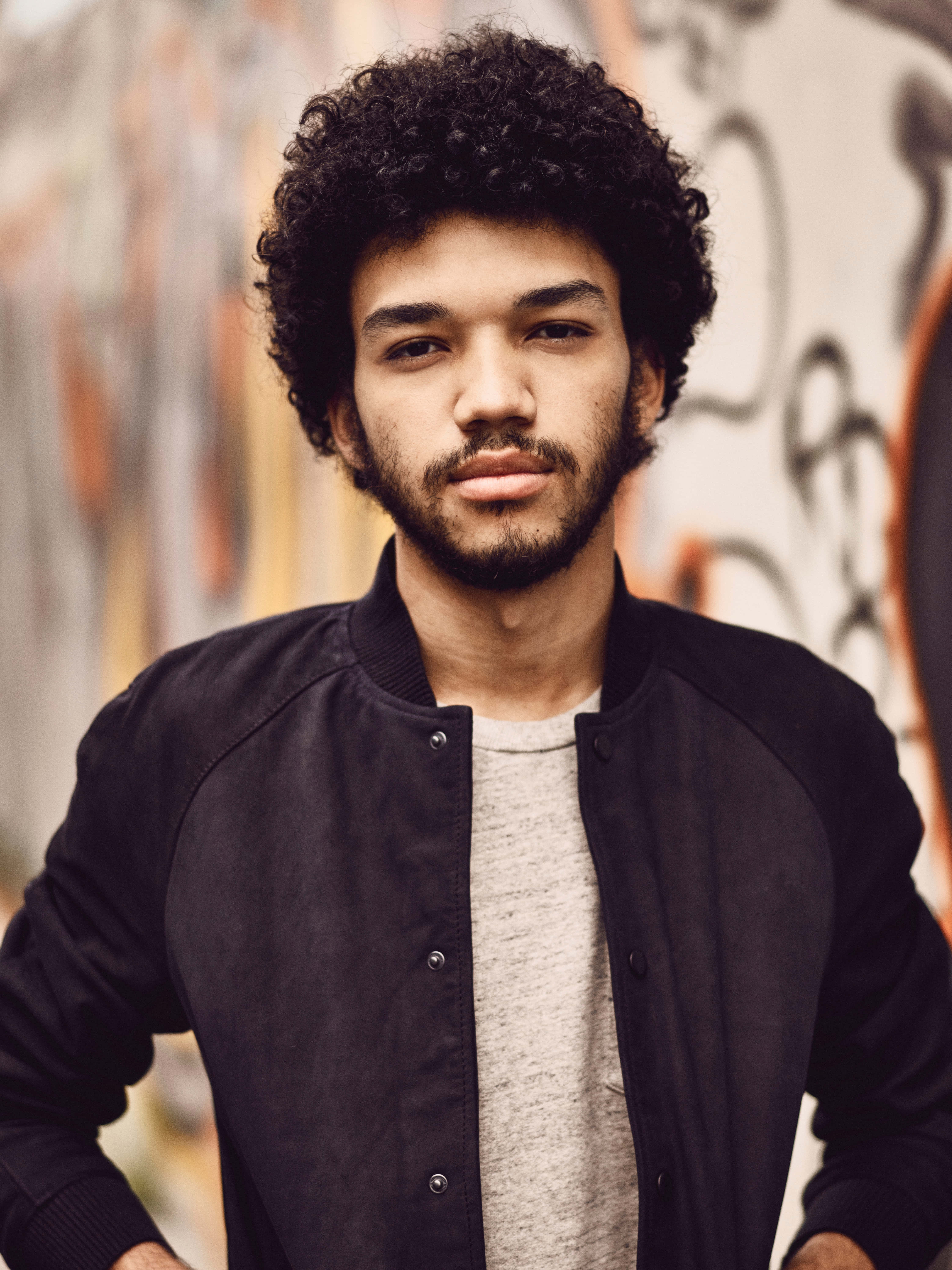 Justice Smith, black bomber jacket, graffiti-covered wall, 5K Phone Wallpaper