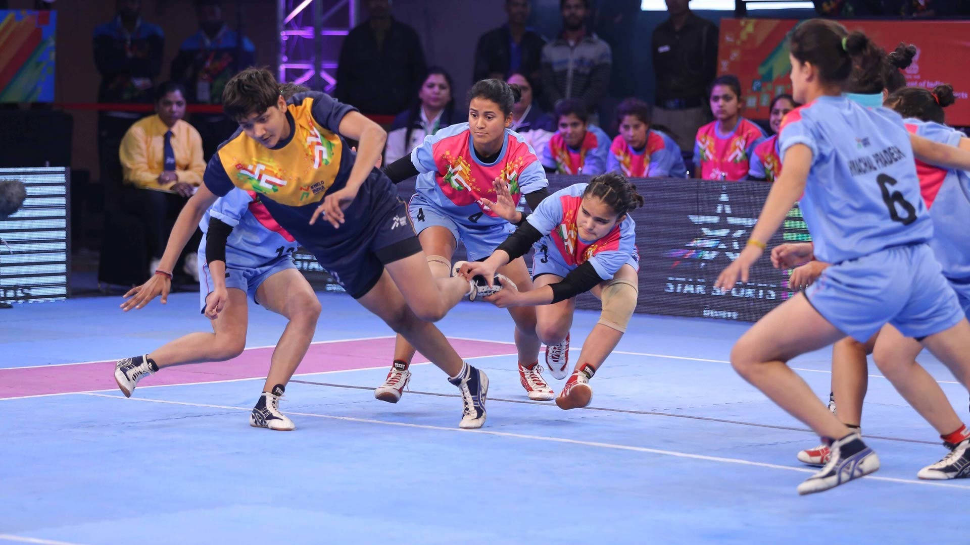 Women's Kabaddi Tackle, vibrant jerseys, blue indoor court, Full HD Desktop Wallpaper