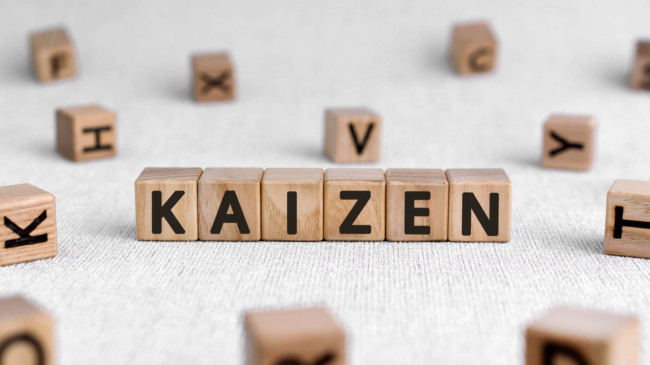 kaizen, wooden letter blocks, textured gray surface, 2K Desktop Wallpaper