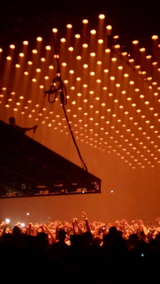 Kanye West Saint Pablo, warm orange stage lights, silhouetted concertgoers, SD Phone Wallpaper