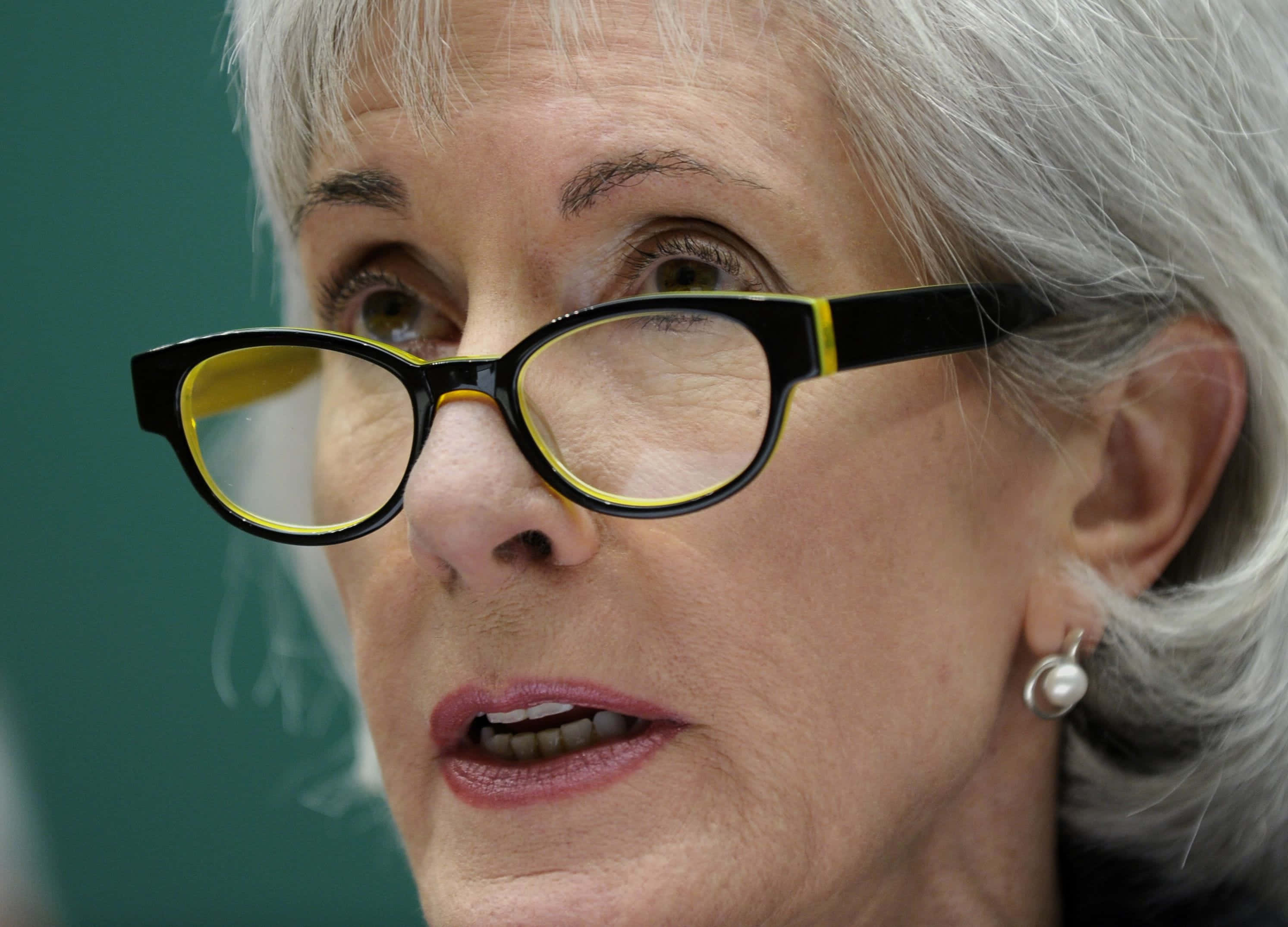 Kathleen Sebelius, gray hair, black-framed glasses with yellow accents, 2K Desktop Wallpaper