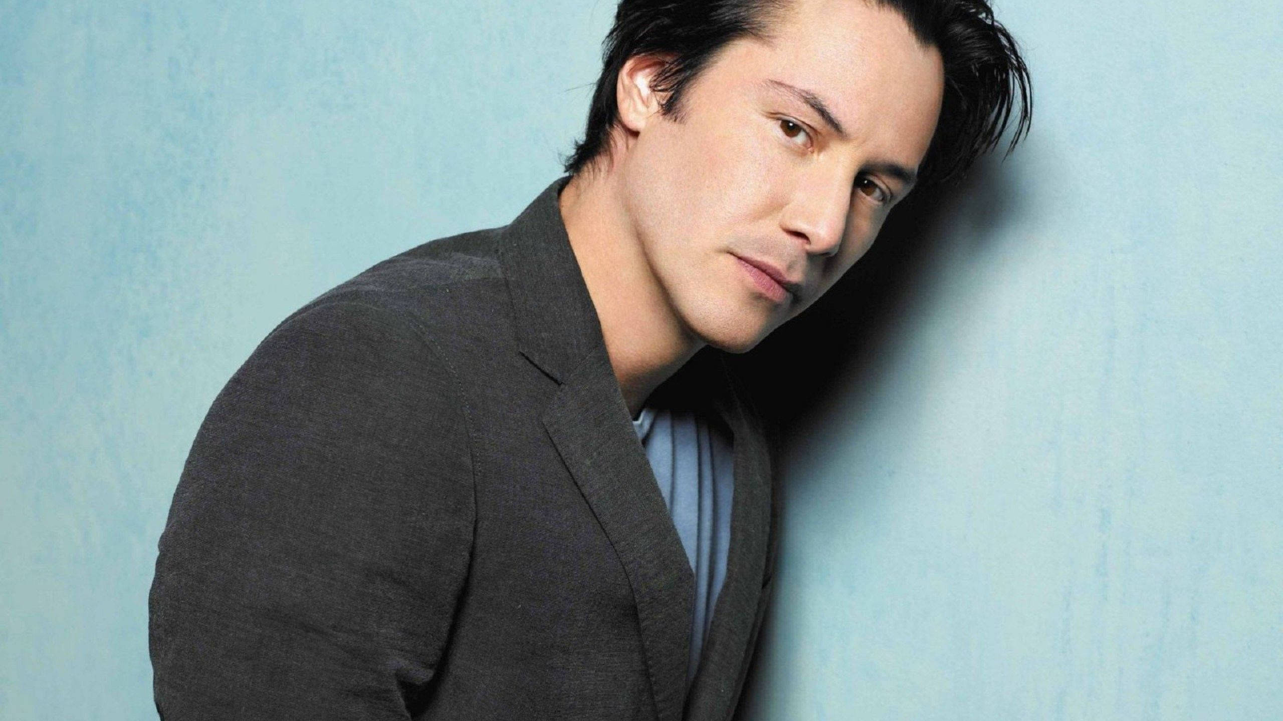 Keanu Reeves, dark blazer, textured blue wall, 2K Desktop Wallpaper