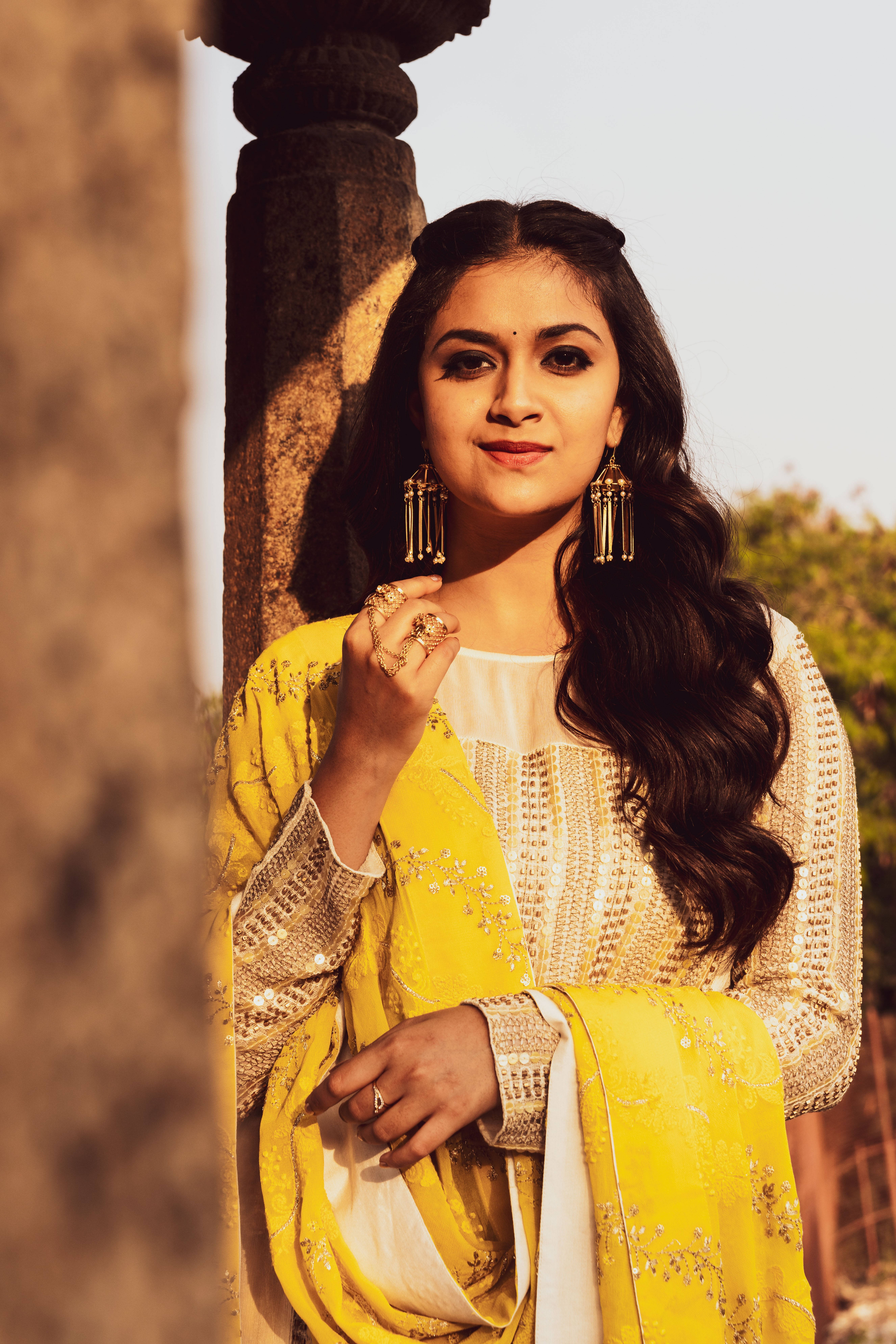 Keerthi Suresh, yellow embroidered outfit, weathered stone pillar, 8K Phone Wallpaper