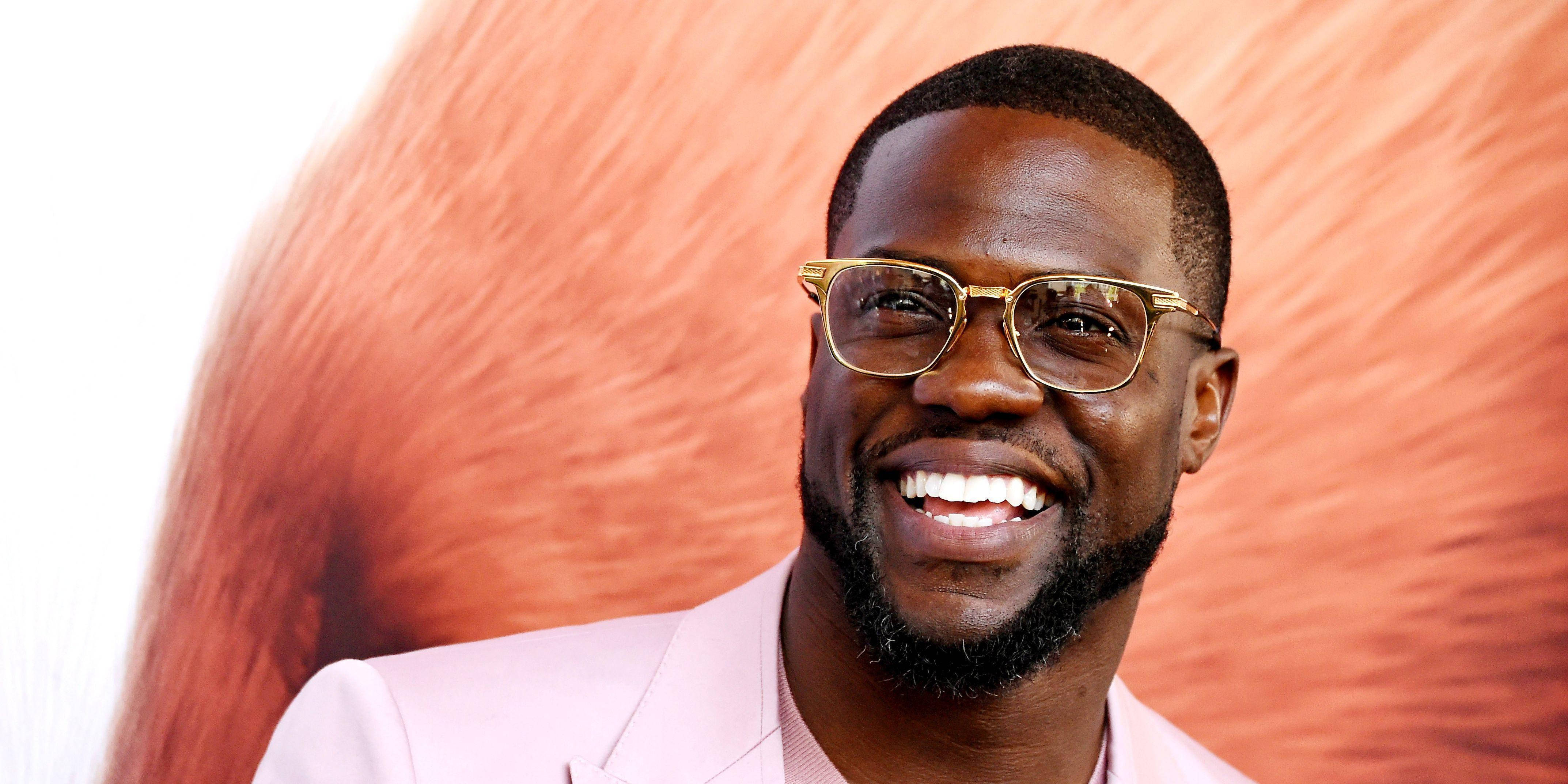 Kevin Hart, gold-rimmed glasses, textured orange backdrop, 4K Desktop Wallpaper
