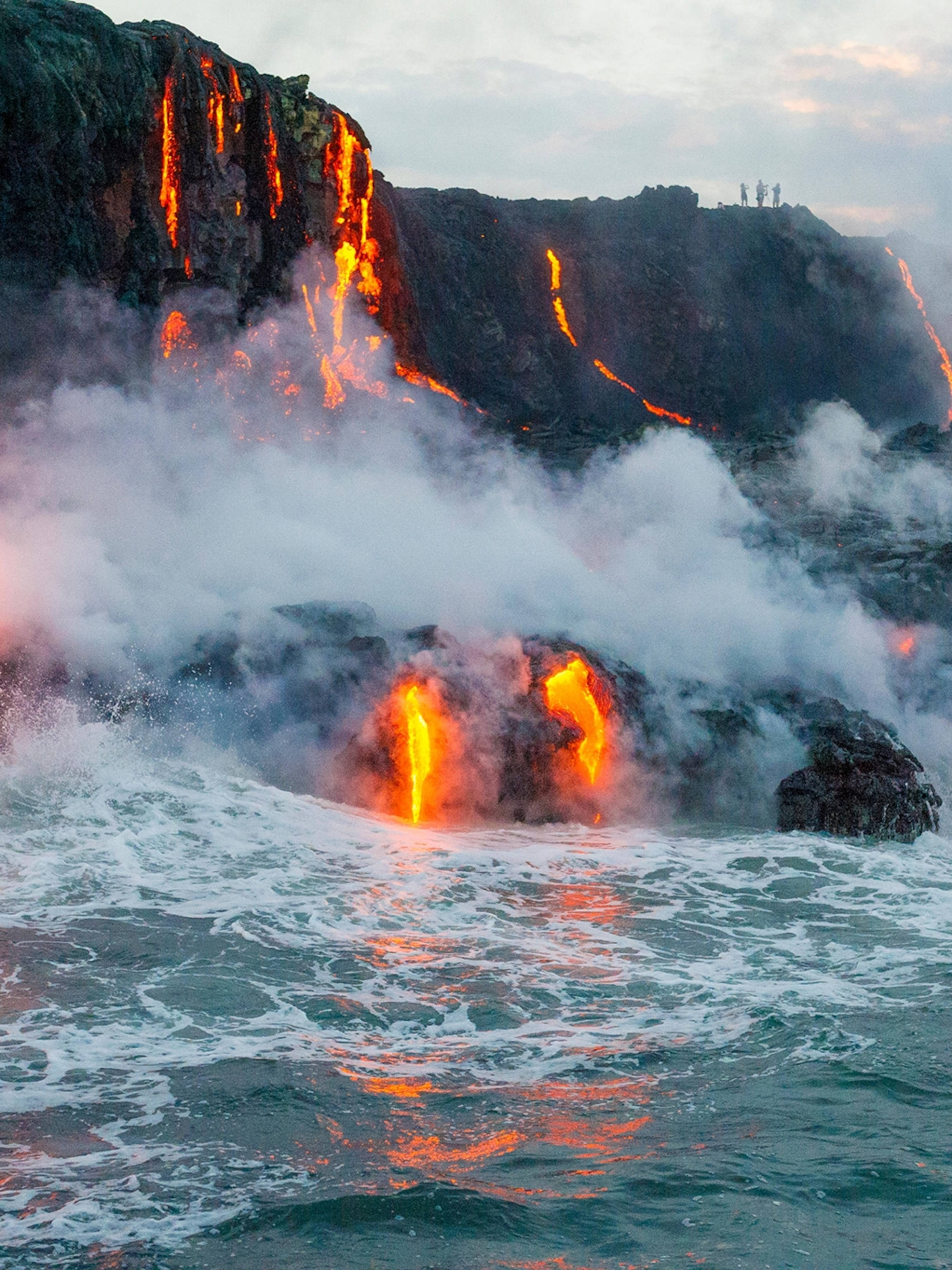 Kilauea Volcano, lava flowing to ocean, glowing orange reflections, 2K Phone Wallpaper