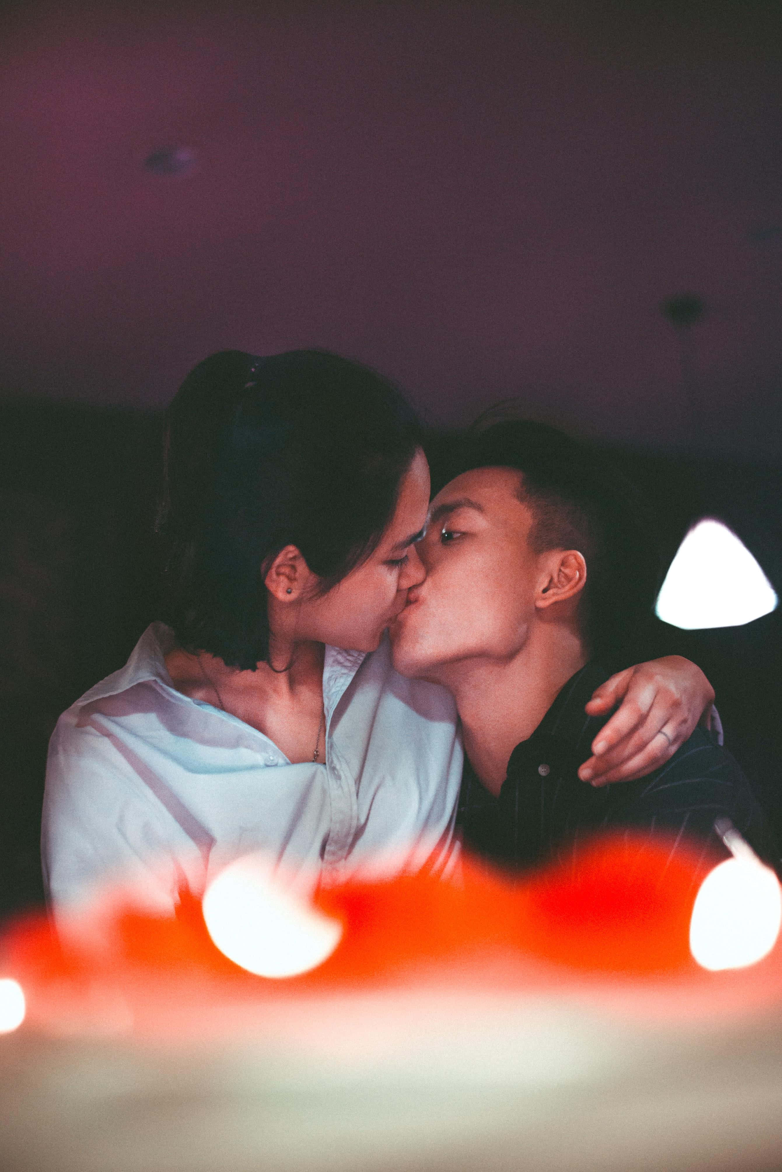 Sweet Woman Kissing His Lips, warm ambient lighting, blurred red bokeh lights, 4K Phone Wallpaper