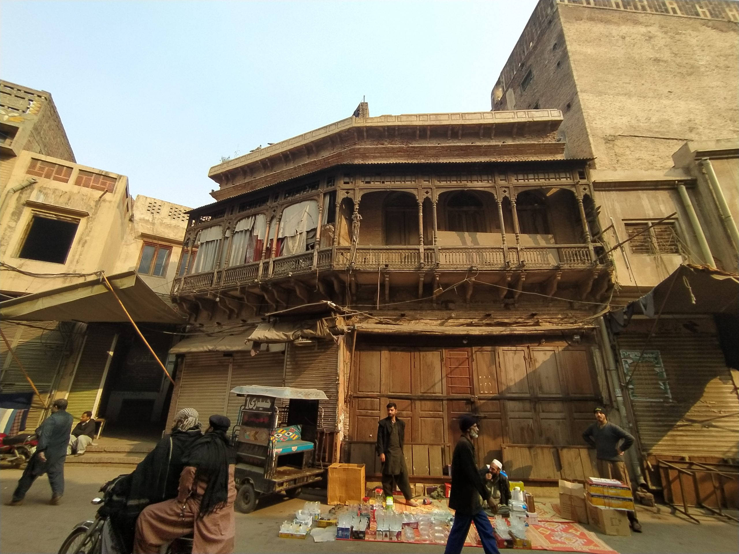 Lahore, rundown building, bustling street scene, 2K Desktop Wallpaper
