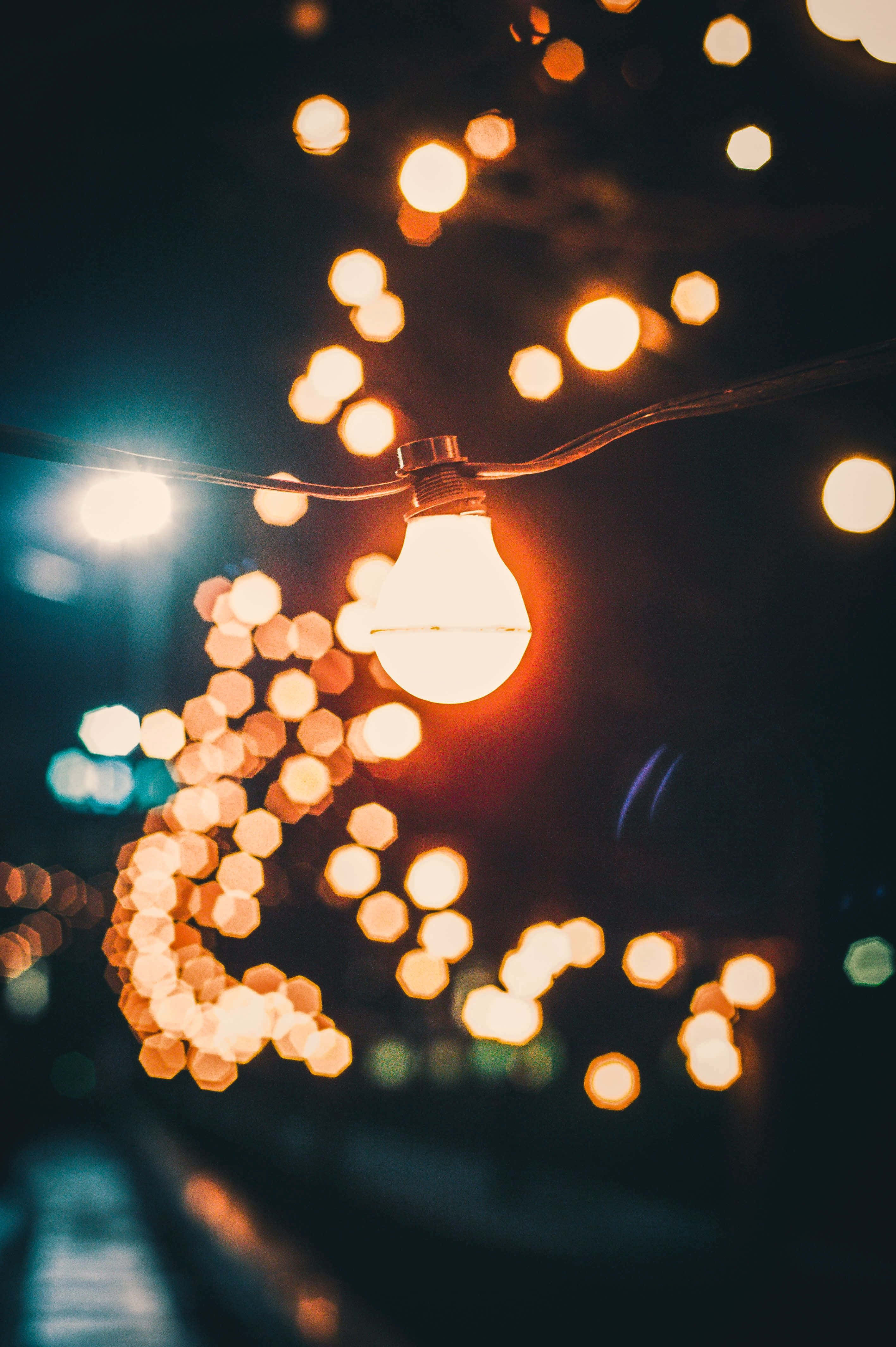 glowing light bulb, dark background, warm golden bokeh lights, 4K Phone Wallpaper