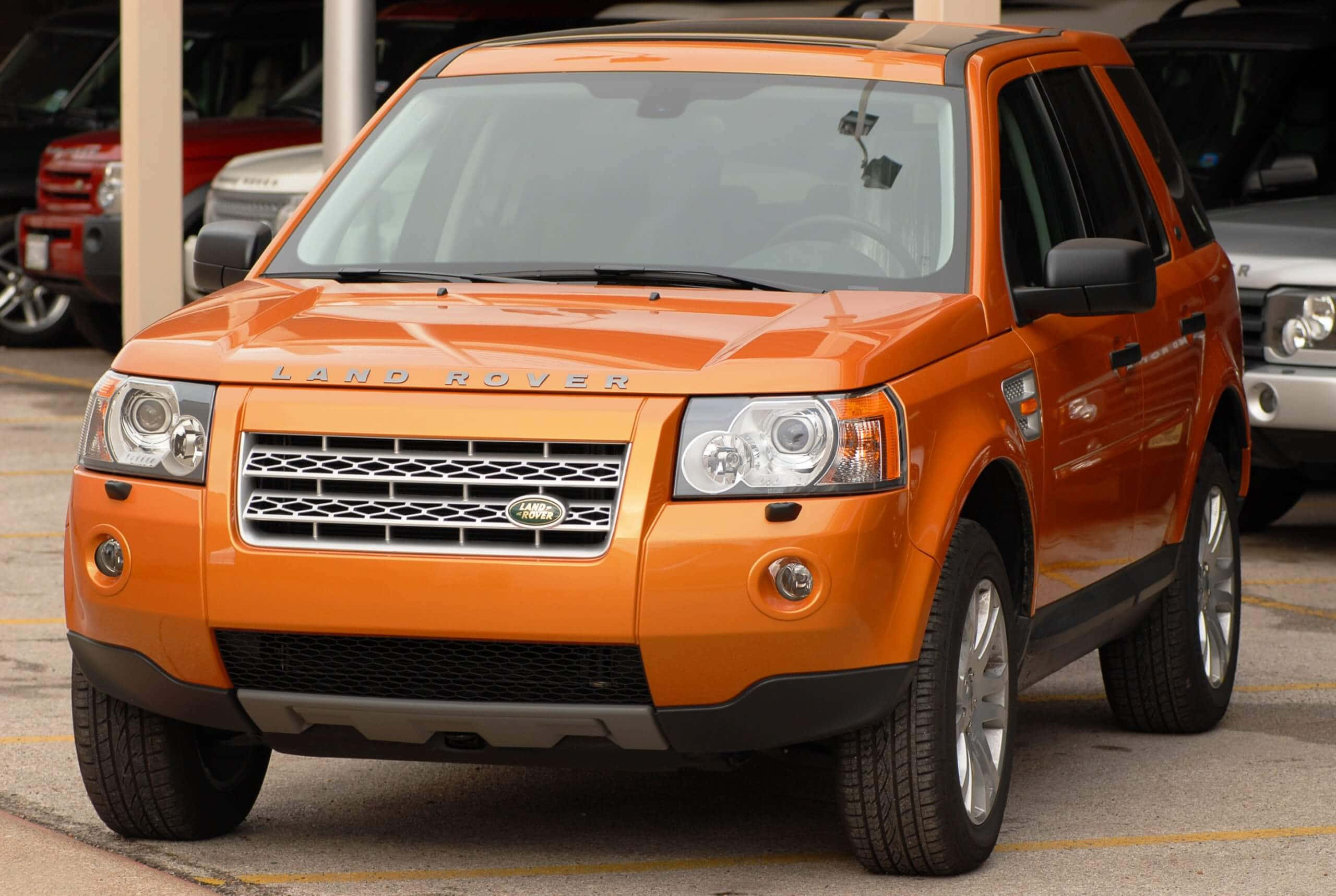 Land Rover Freelander, vibrant orange, parked in a lot, 2K Desktop Wallpaper