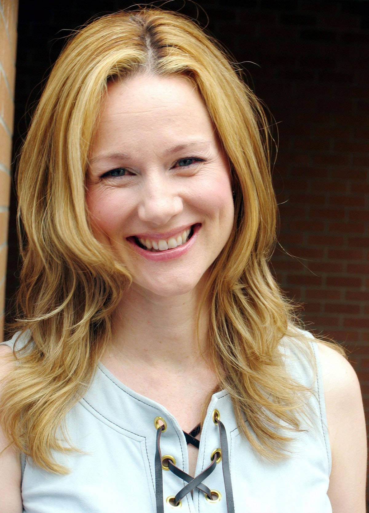 Laura Linney, blonde hair, brick wall, HD Phone Wallpaper