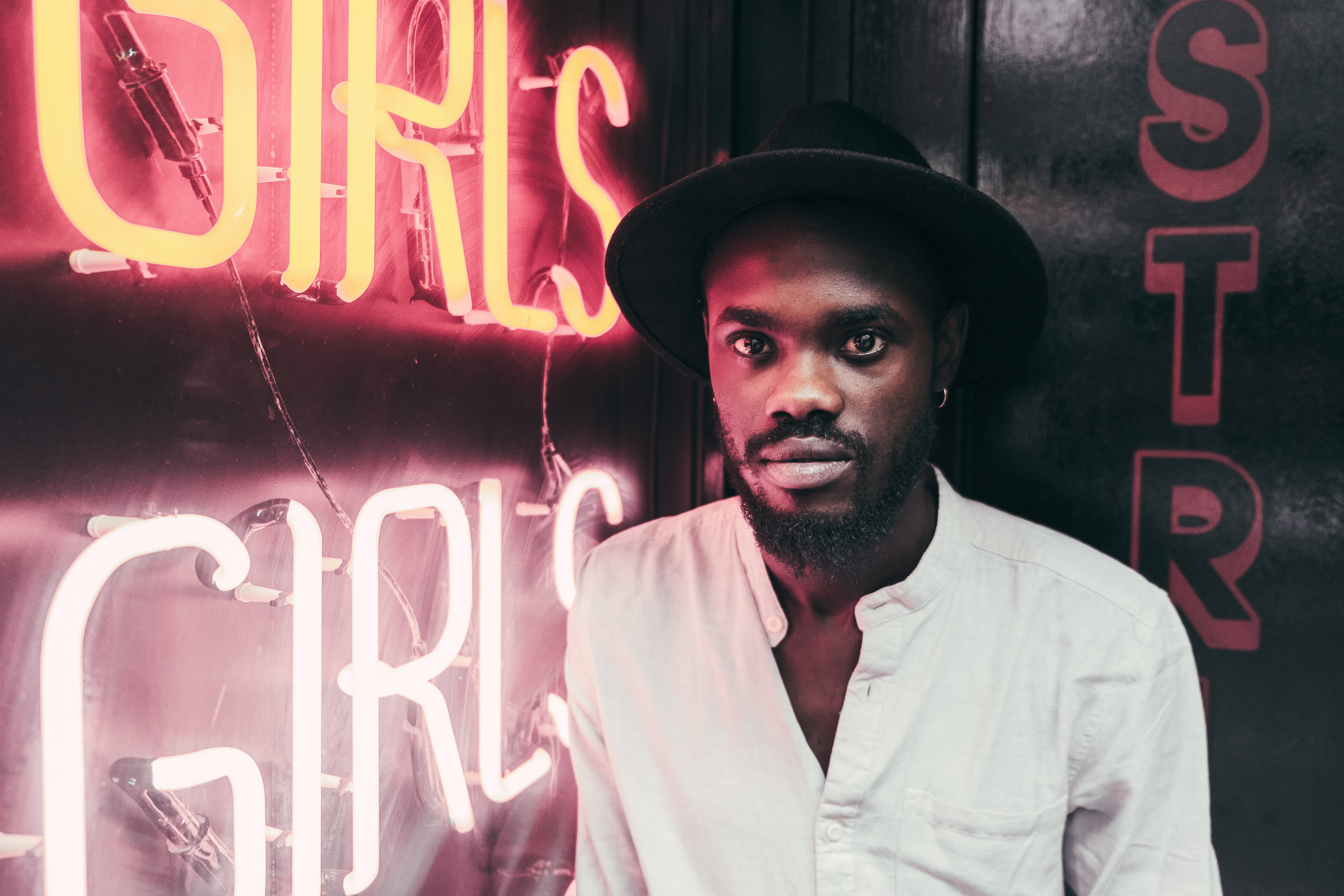 African man, black hat, glowing pink and yellow neon signs, 5K Desktop Wallpaper