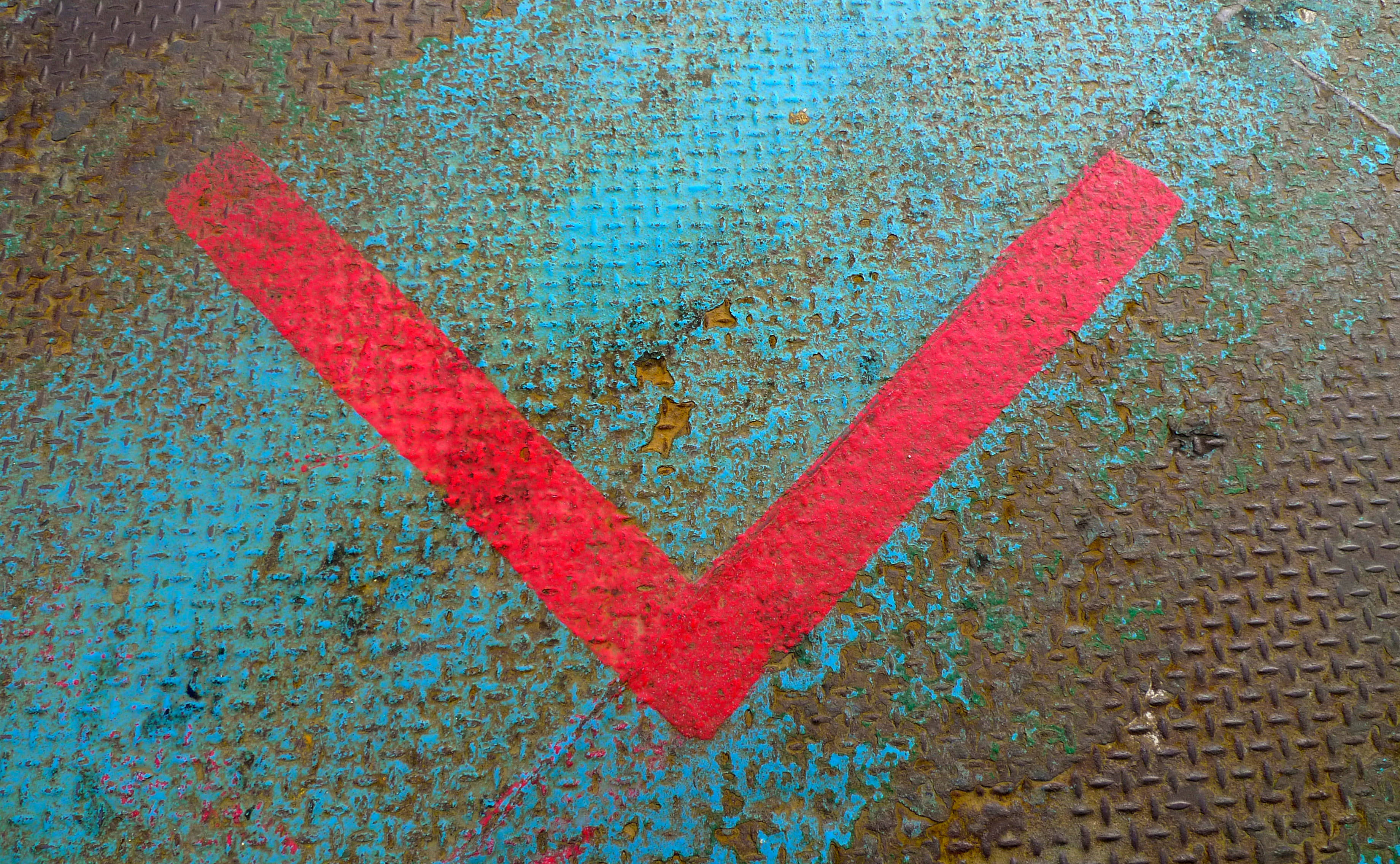 Red V-shaped arrow, weathered blue and rusty metal surface, diamond plate texture, 2K Desktop Wallpaper