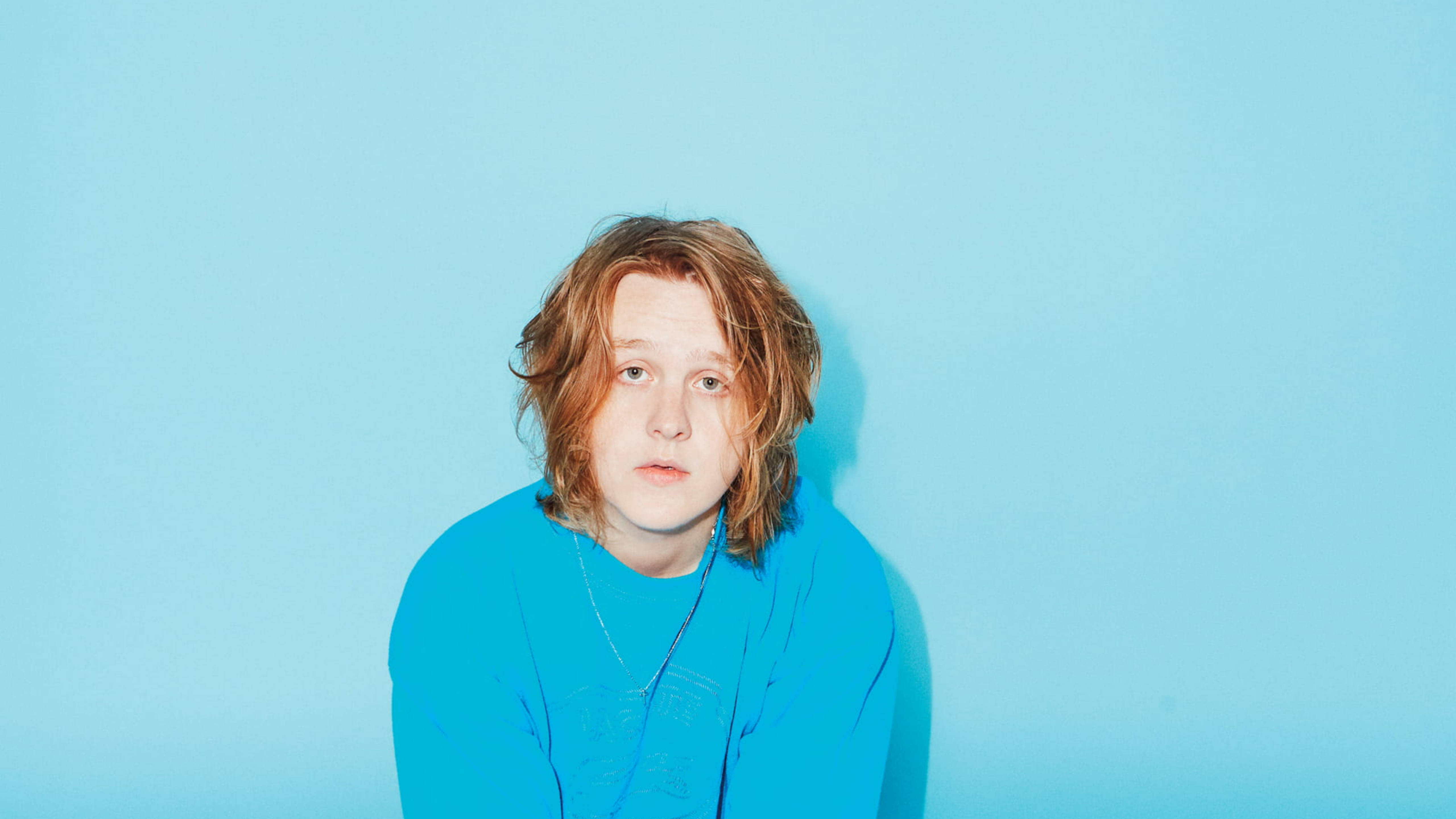 Lewis Capaldi, bright blue shirt, solid light blue studio background, 5K Desktop Wallpaper
