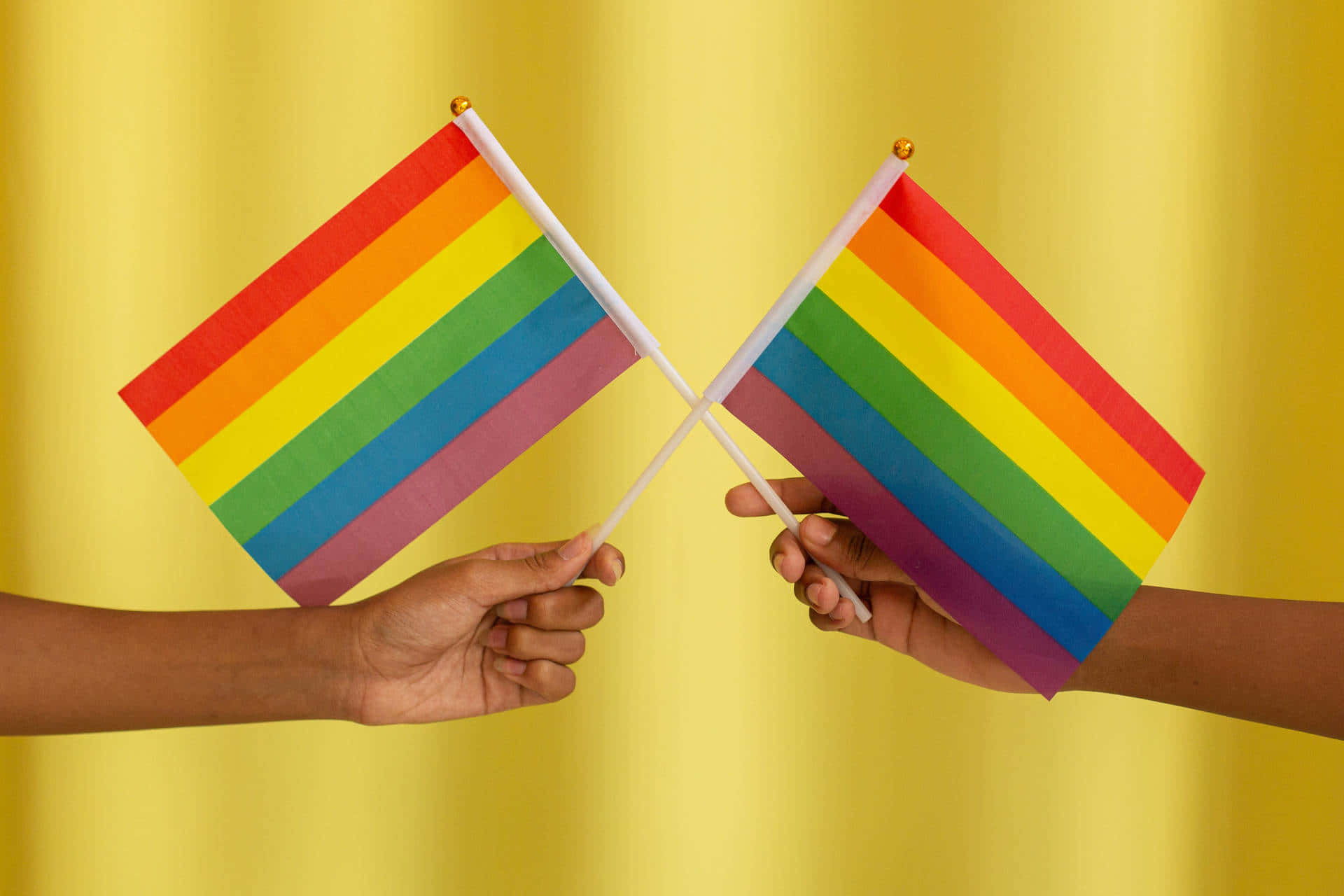 rainbow flags, golden-yellow draped background, two hands, Full HD Desktop Wallpaper