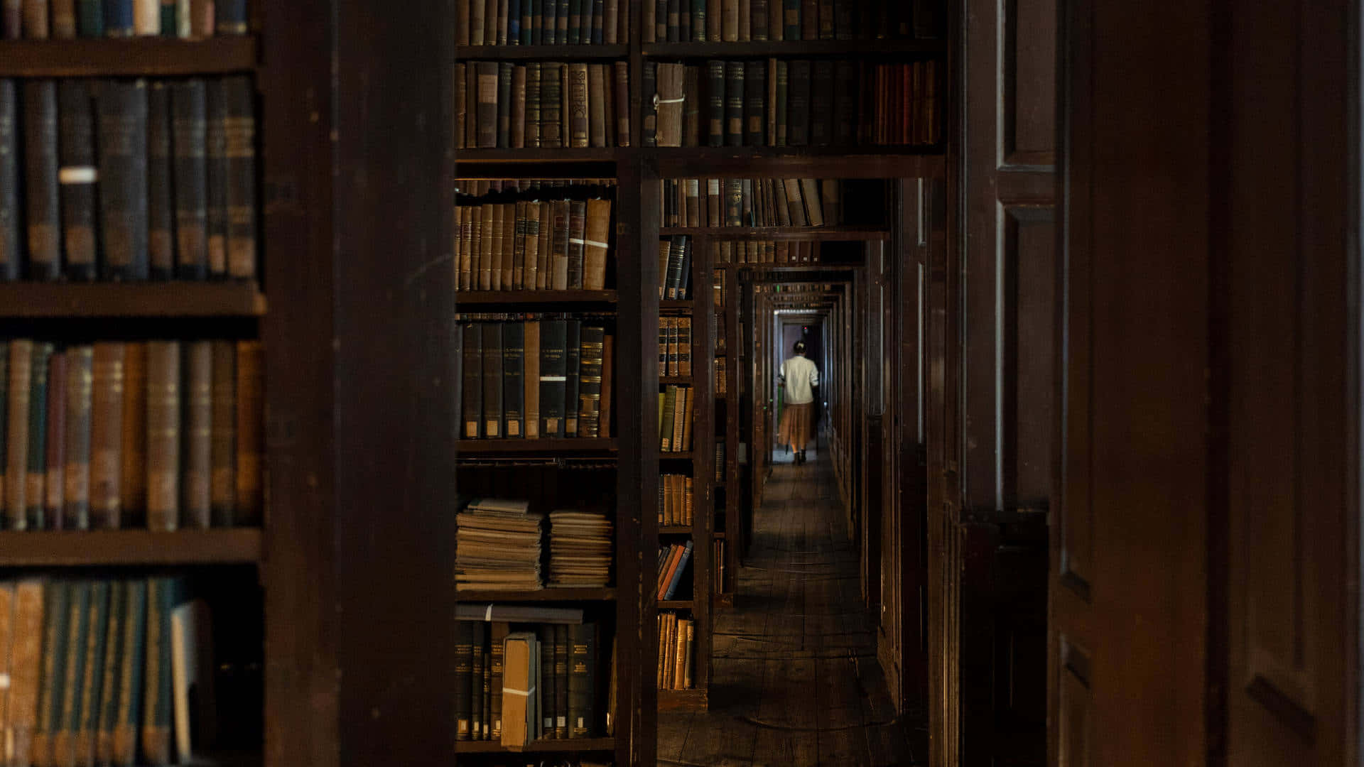 mysterious library corridor, dimly lit wooden aisle, towering bookshelves, Full HD Desktop Wallpaper