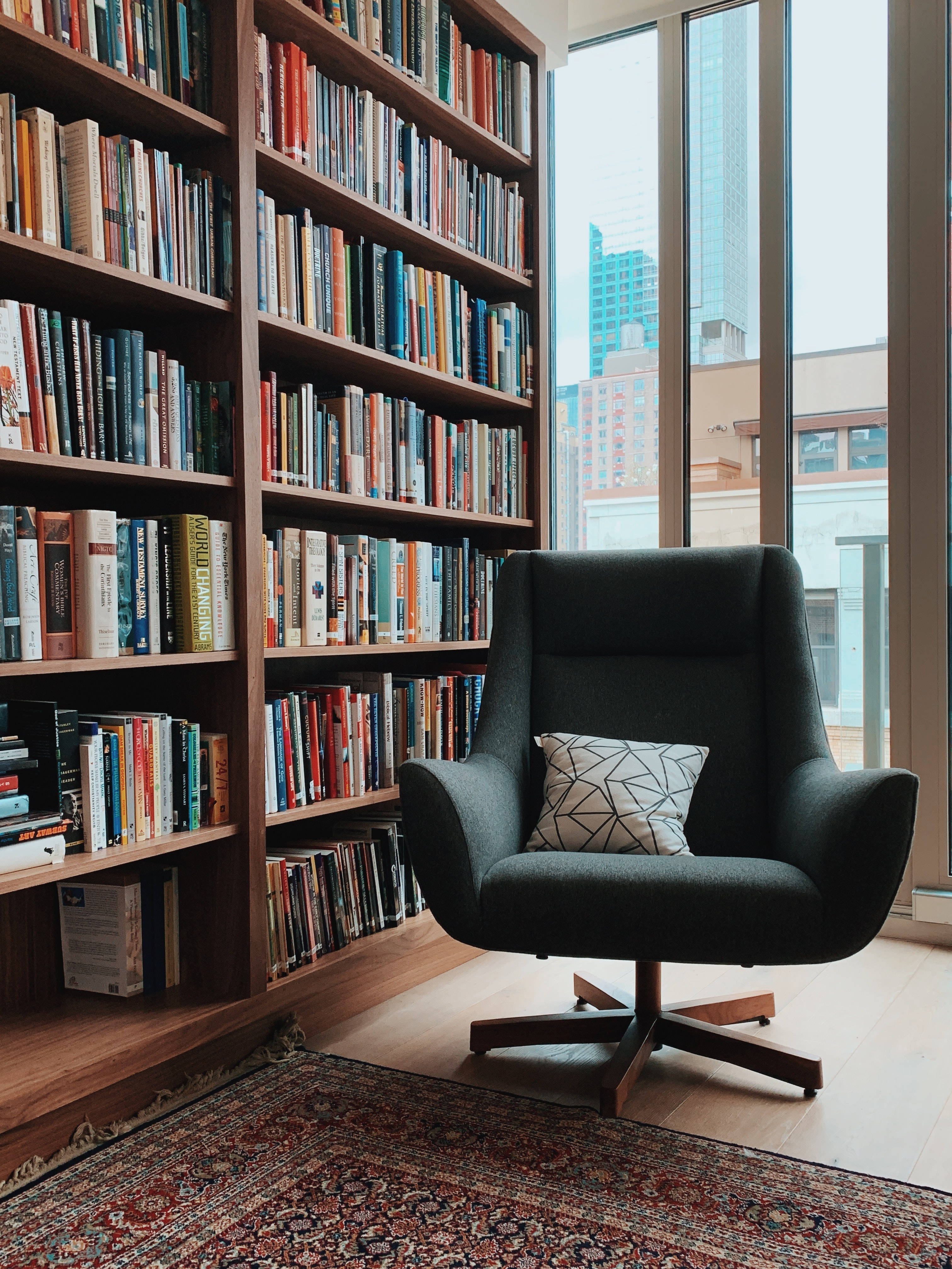 black armchair, patterned pillow, tall bookshelves, 4K Phone Wallpaper