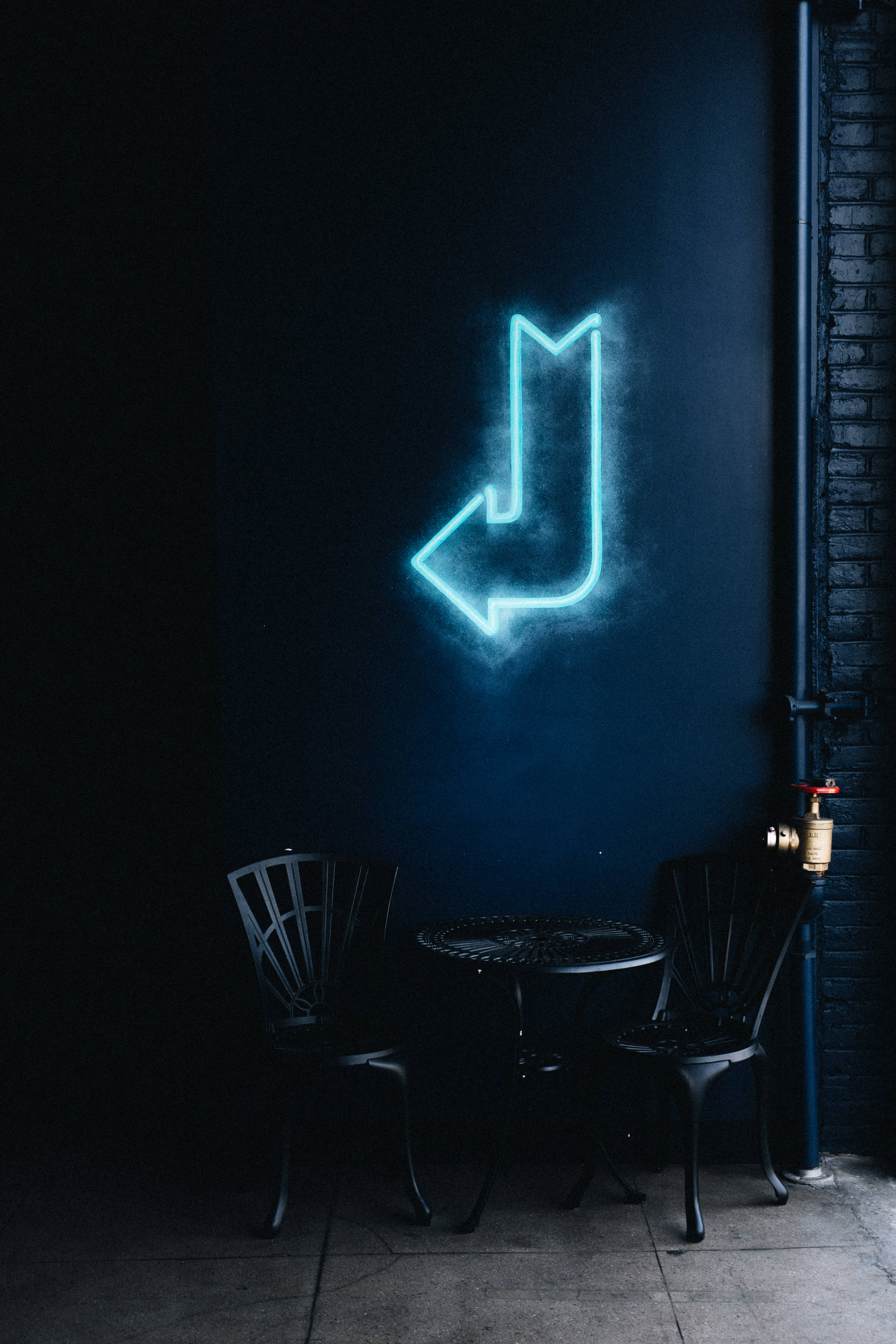 blue neon arrow sign, dark urban alleyway, metal table, 5K Phone Wallpaper