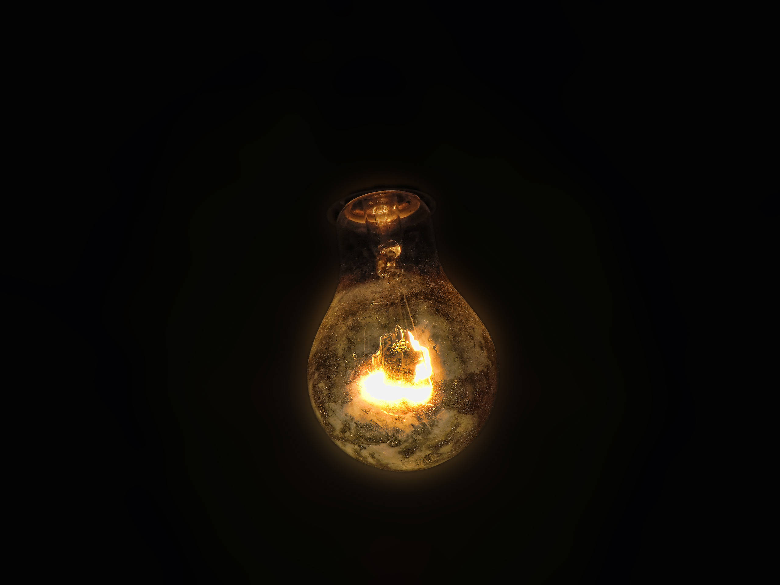 yellow lit light bulb, glowing incandescent bulb, visible filament, 2K Desktop Wallpaper