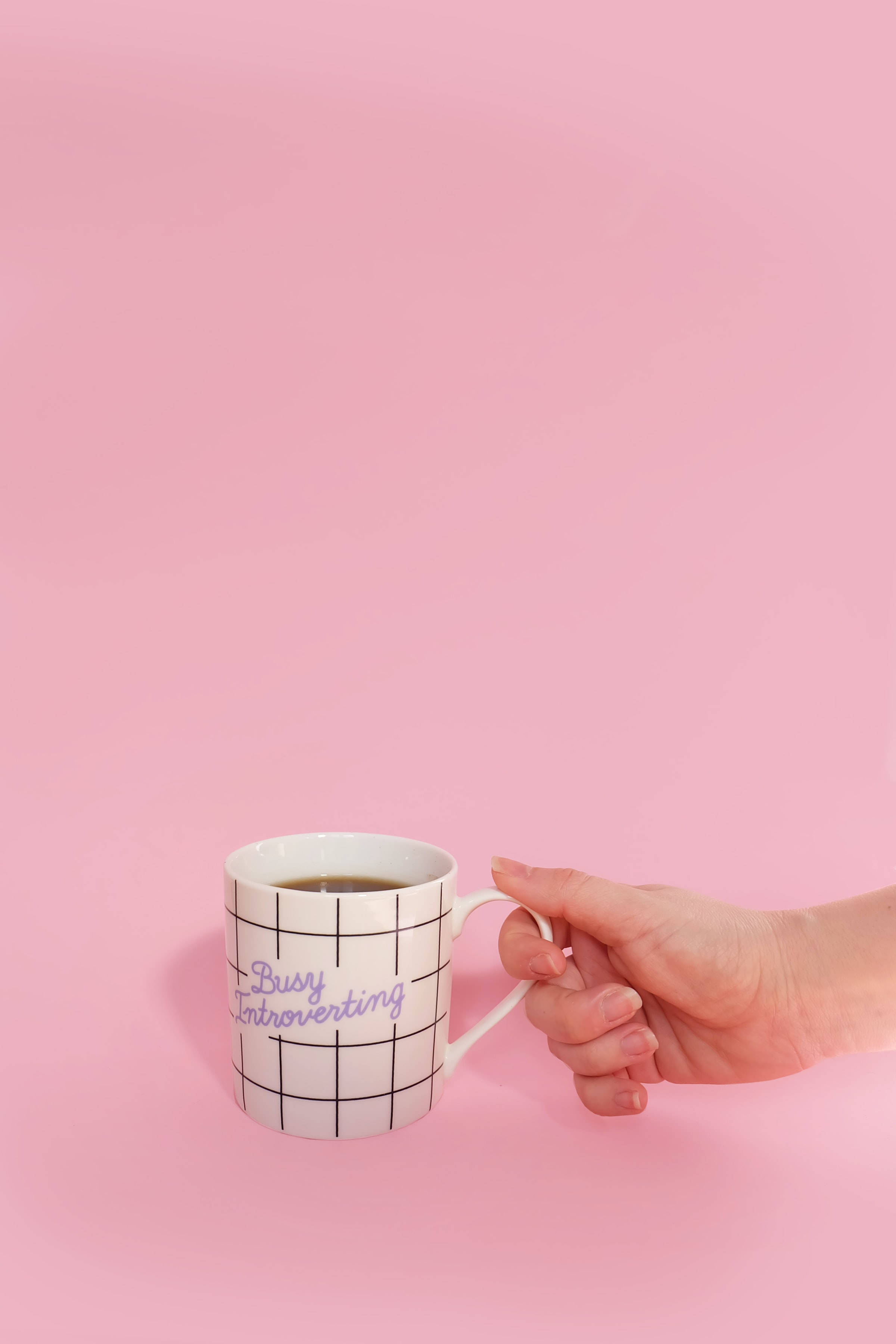 white mug, black grid, purple 'Busy Introverting' text, 2K Phone Wallpaper