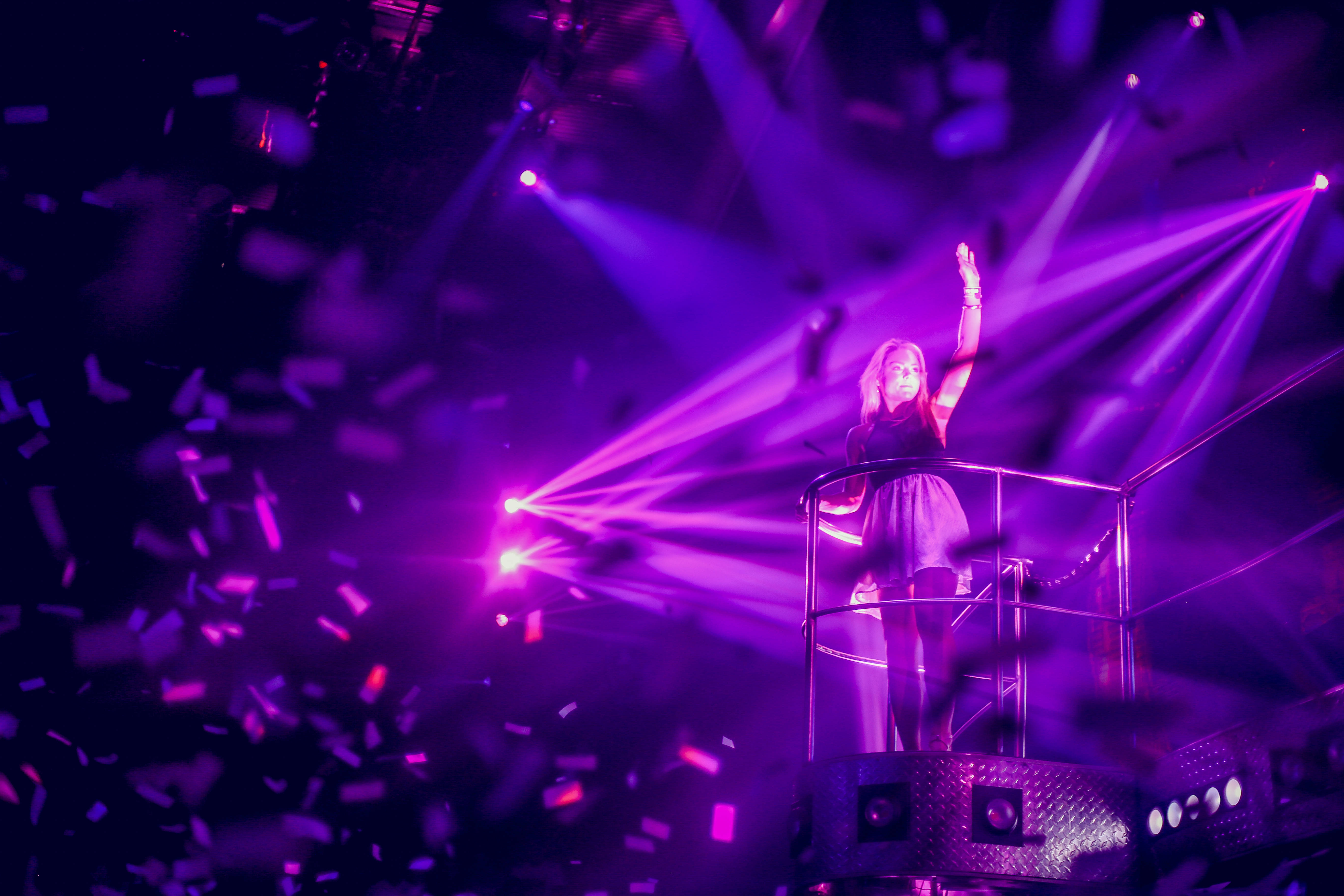 female DJ, raised platform, vibrant purple laser lights, 5K Desktop Wallpaper