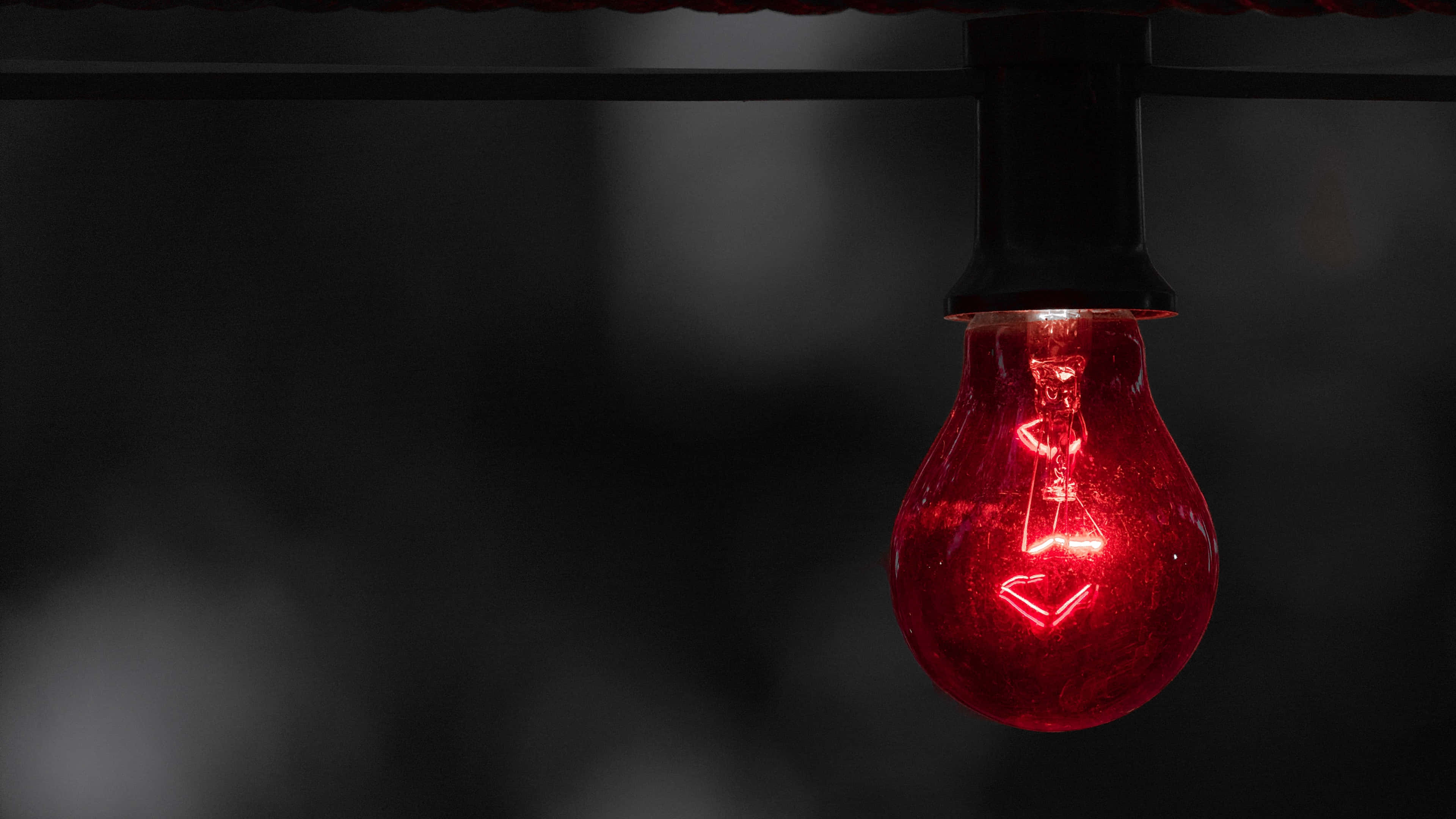 red light bulb, glowing, dark blurred background, 4K Desktop Wallpaper