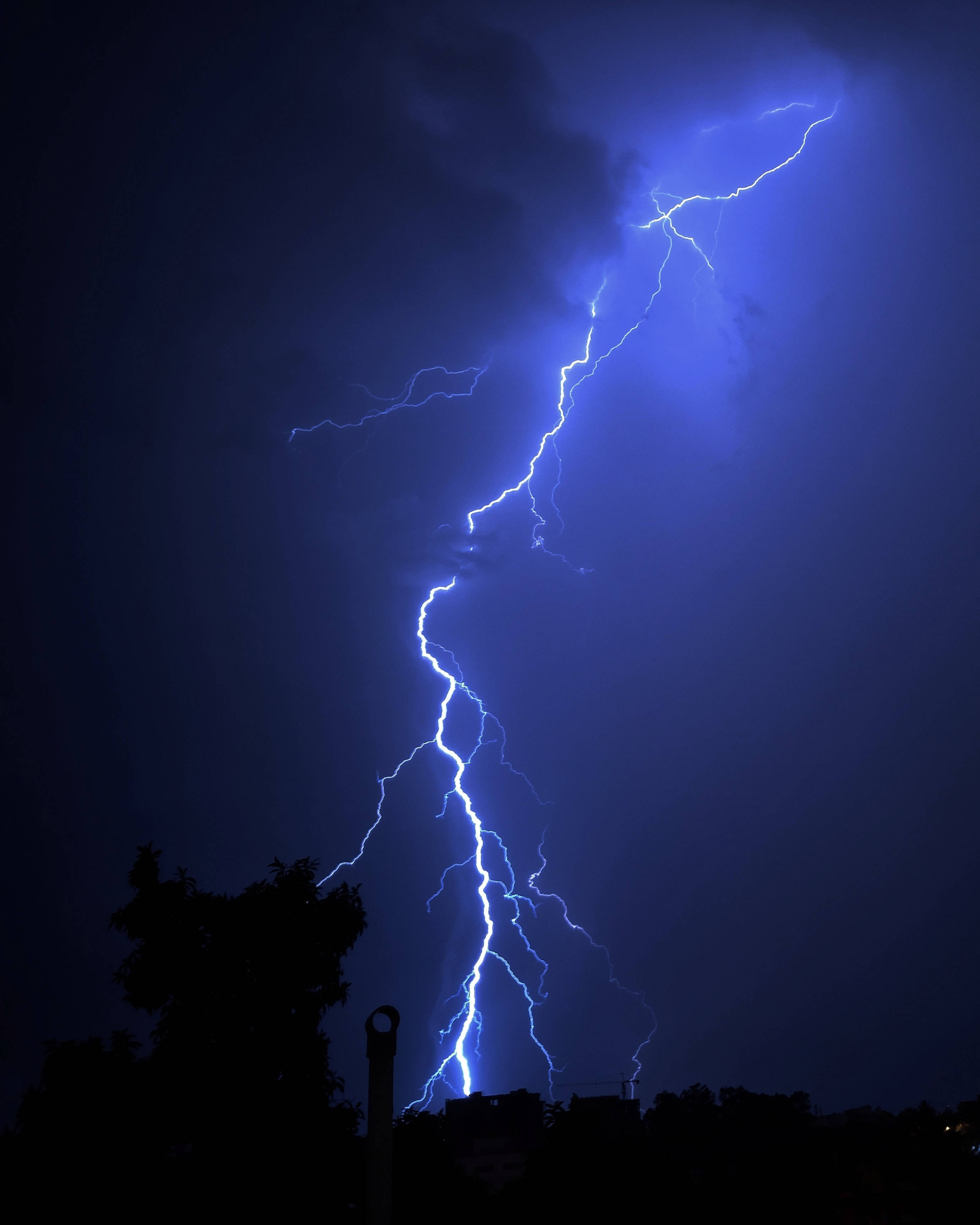 blue lightning bolt, dark stormy sky, silhouetted trees, 2K Phone Wallpaper