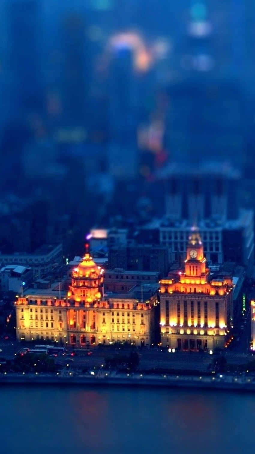 Lit iPhone, nighttime cityscape, warmly lit historic buildings, HD Phone Wallpaper