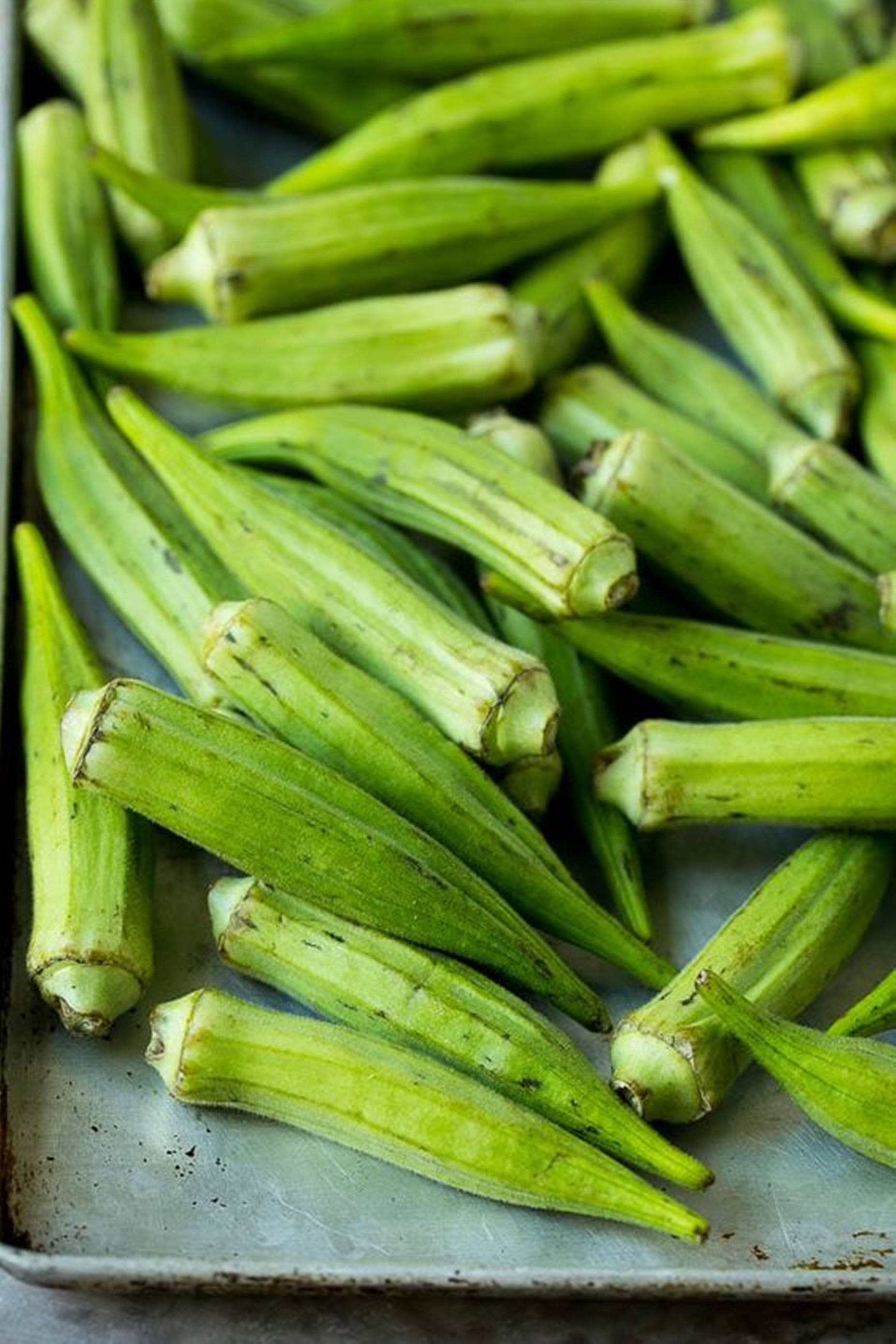 fresh okra pods, weathered metal baking sheet, natural light, 2K Phone Wallpaper