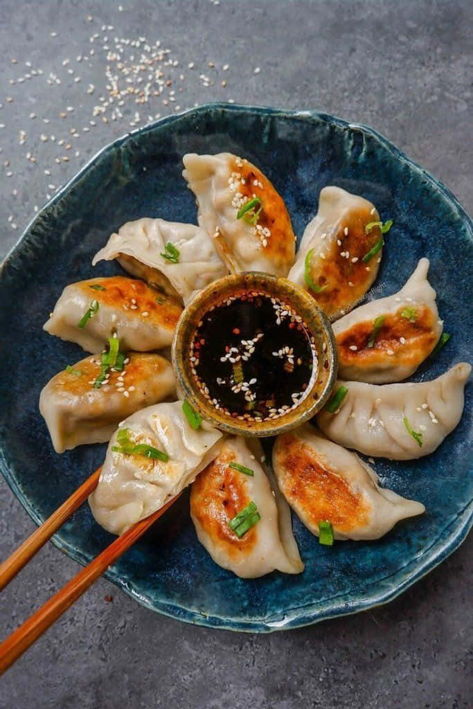 golden-brown pan-fried dumplings, blue ceramic plate, dipping sauce, SD Phone Wallpaper