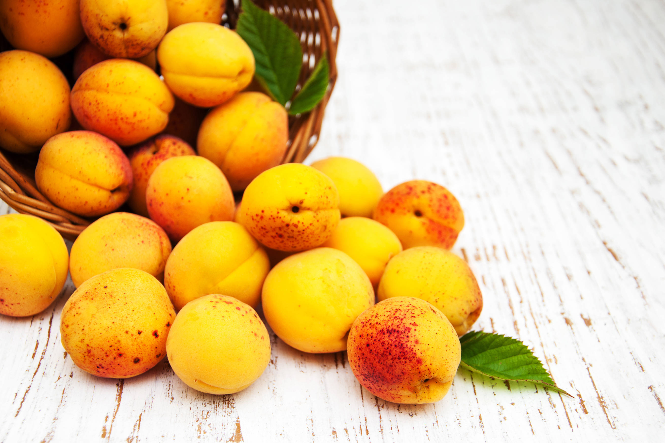 loquat fruit, woven basket, weathered white wooden surface, 2K Desktop Wallpaper