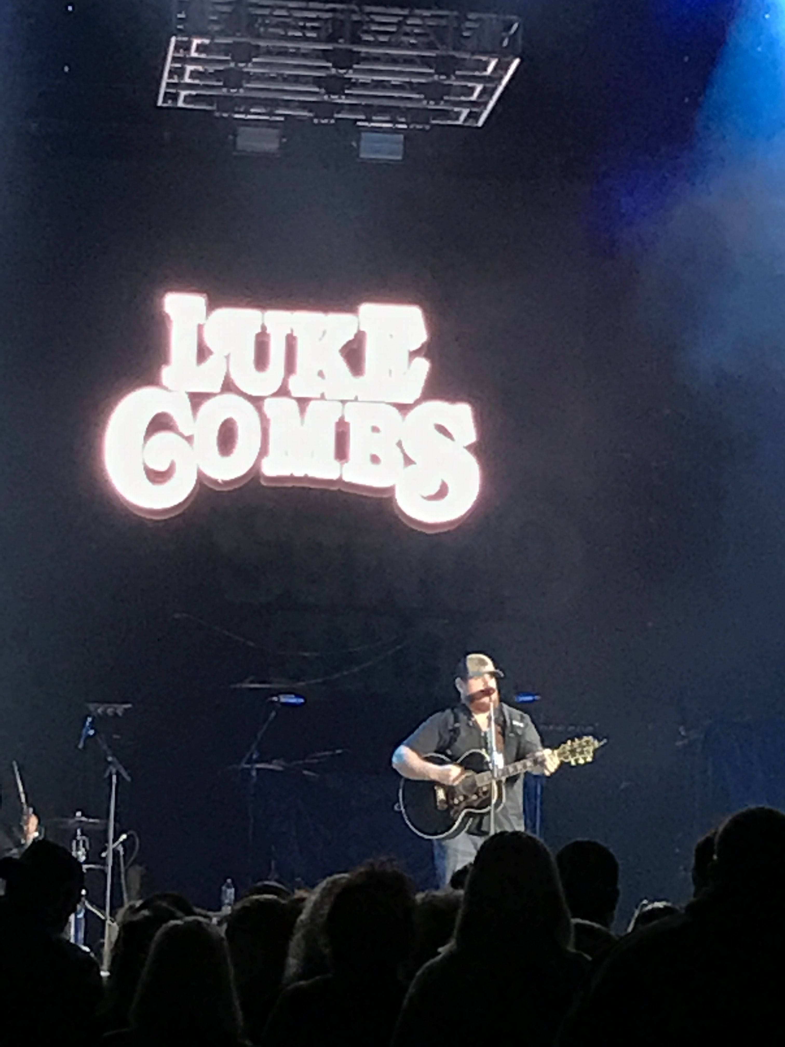 Luke Combs, glowing sign, dim blue-lit concert hall, 4K Phone Wallpaper