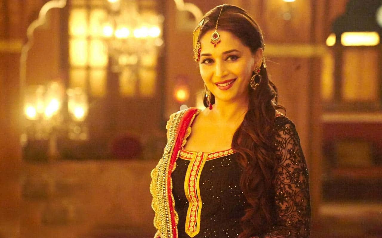 Madhuri Dixit, ornate black and gold traditional attire, warmly lit opulent indoor setting, HD Desktop Wallpaper