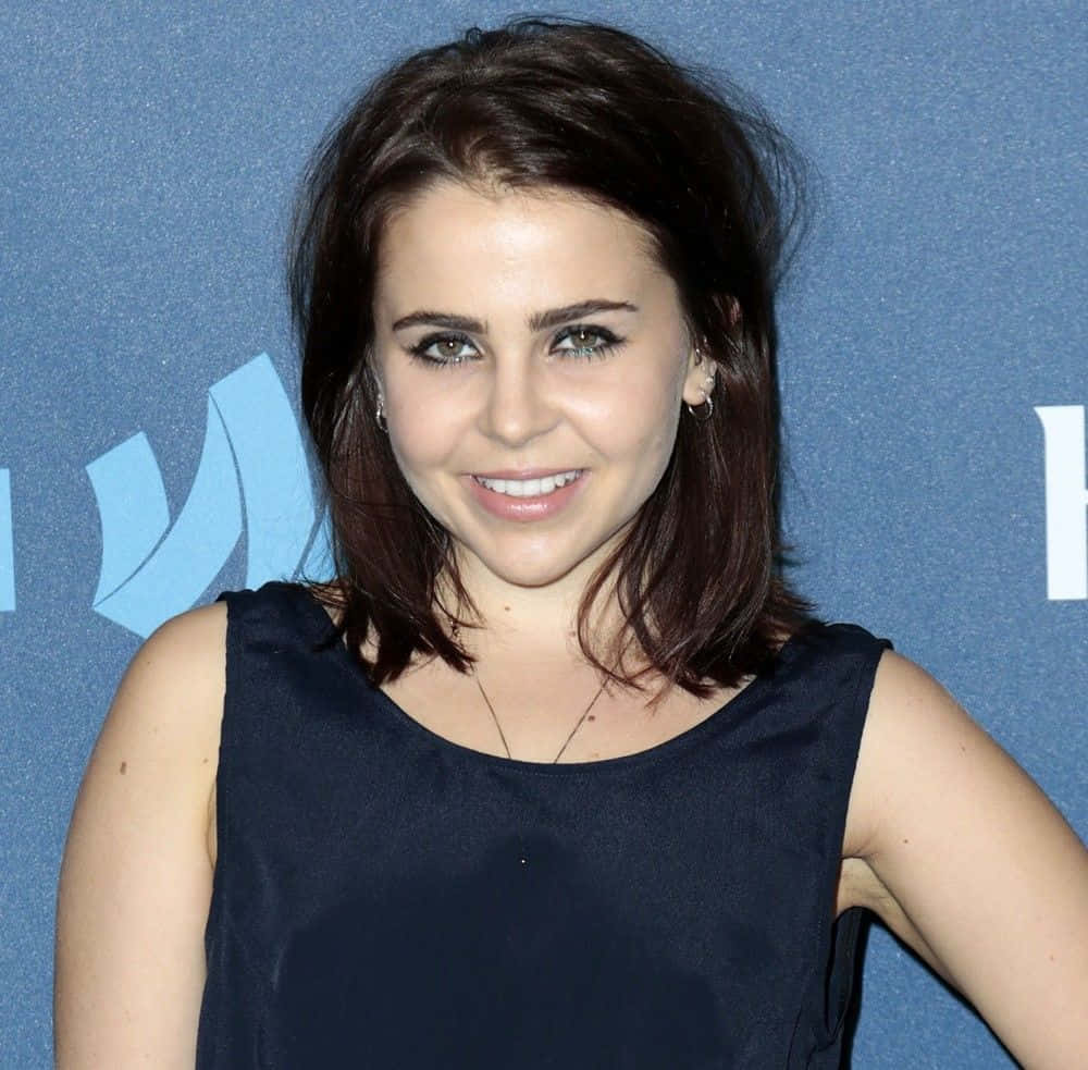 Mae Whitman, navy sleeveless top, blue branded backdrop, SD Desktop Wallpaper