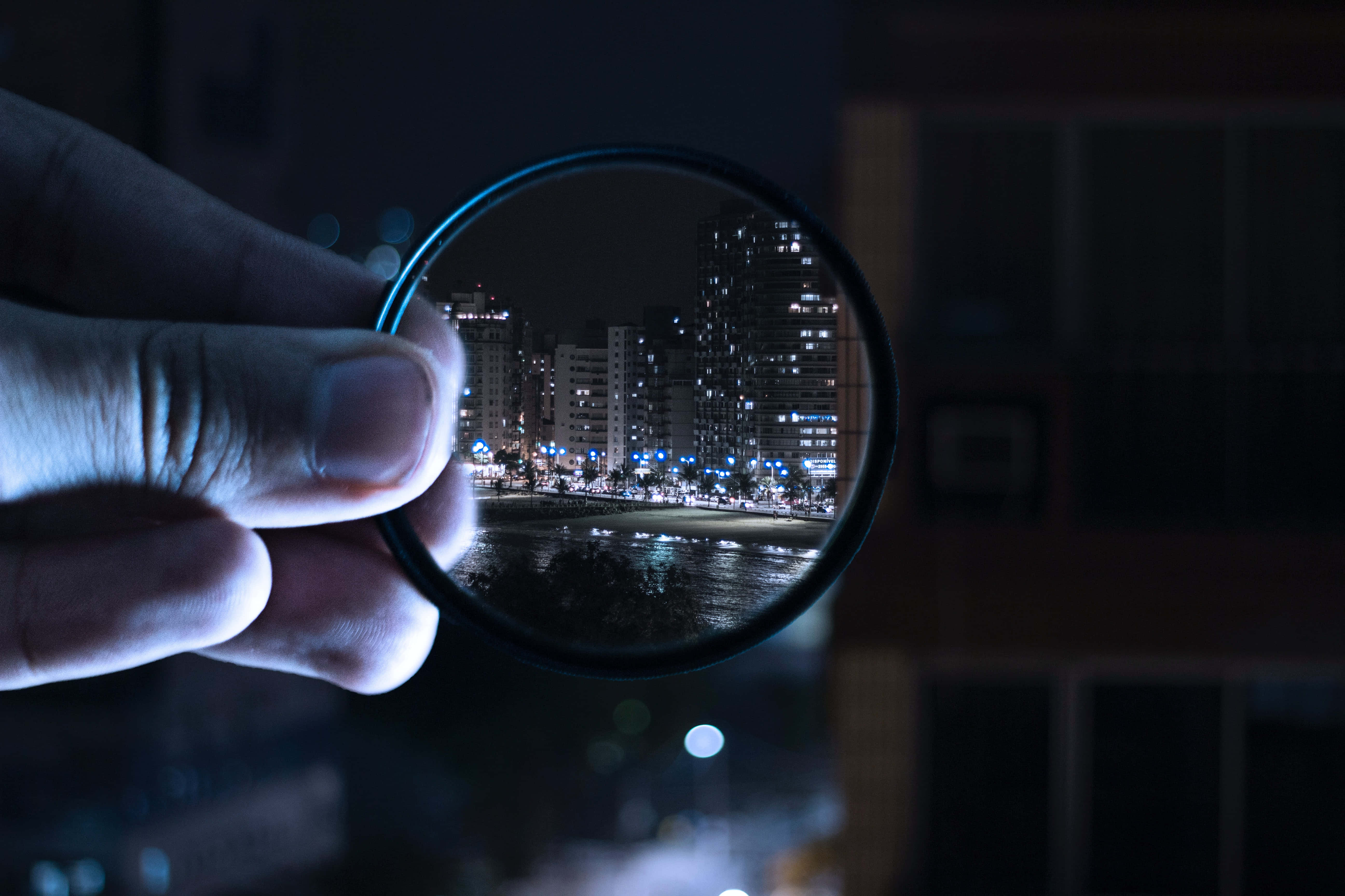 magnifying glass, nighttime cityscape, glowing buildings, 5K Desktop Wallpaper