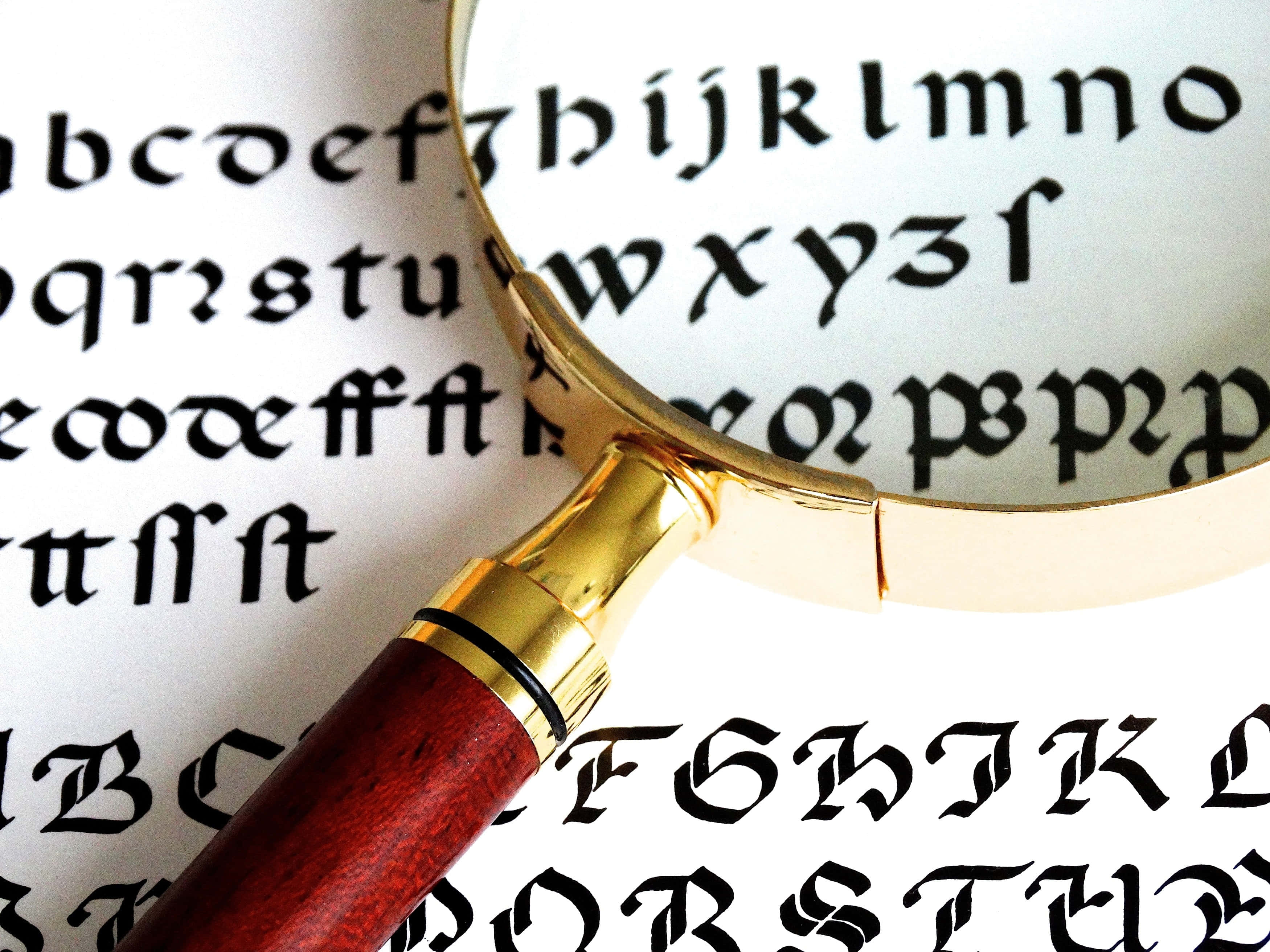 gold-rimmed magnifying glass, wooden handle, blackletter typography, 2K Desktop Wallpaper