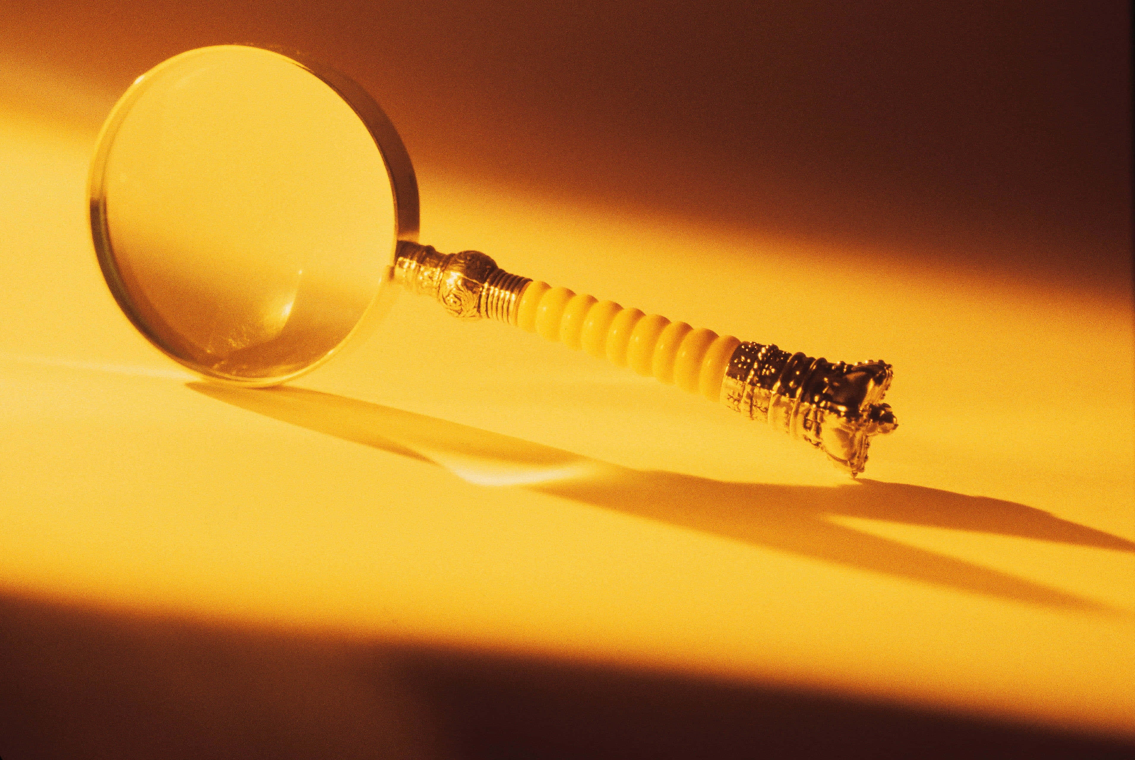 vintage magnifying glass, ornate gold handle, warm amber surface, 2K Desktop Wallpaper