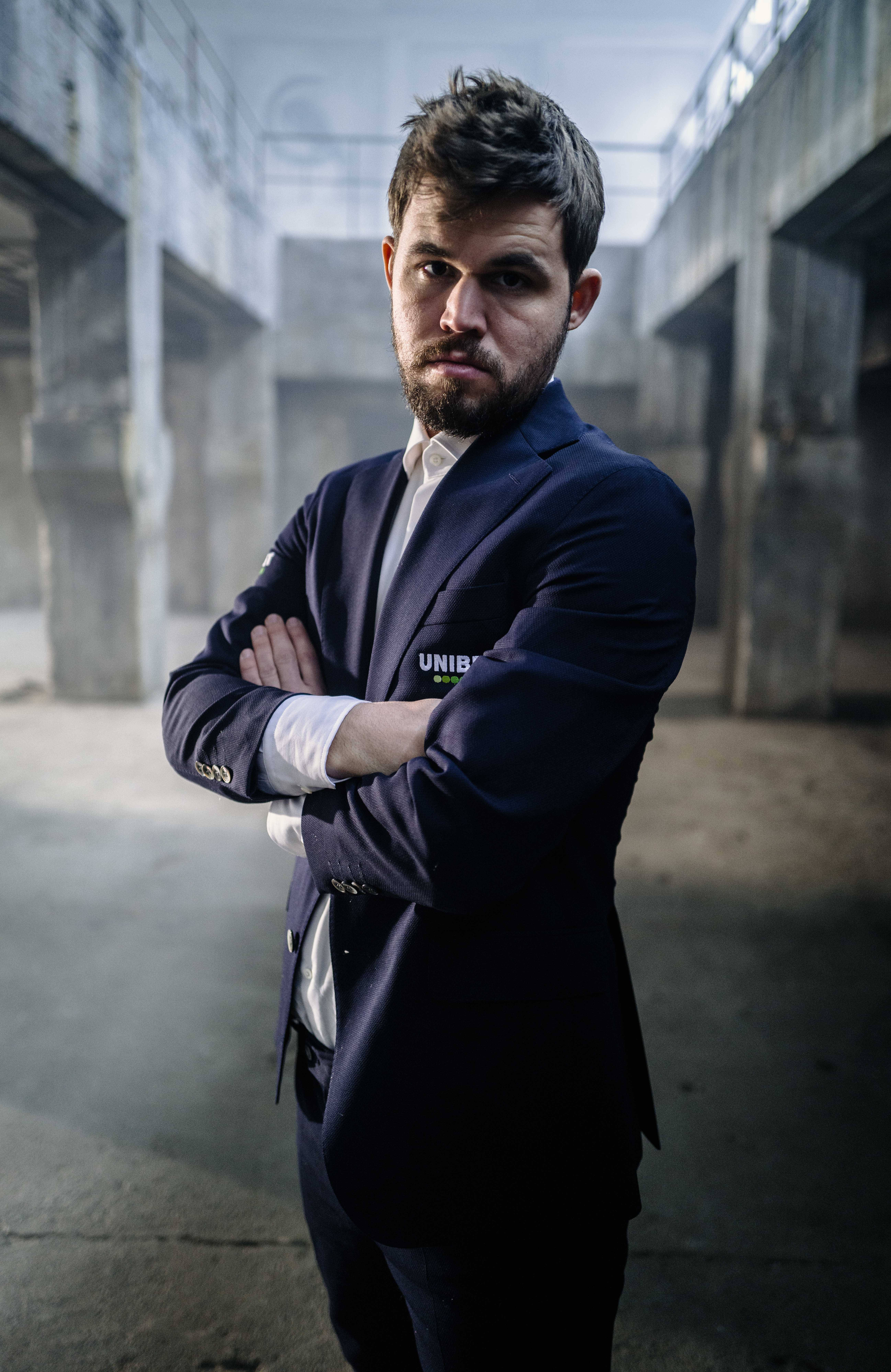 Magnus Carlsen, navy suit, dimly lit concrete industrial space, 8K Phone Wallpaper