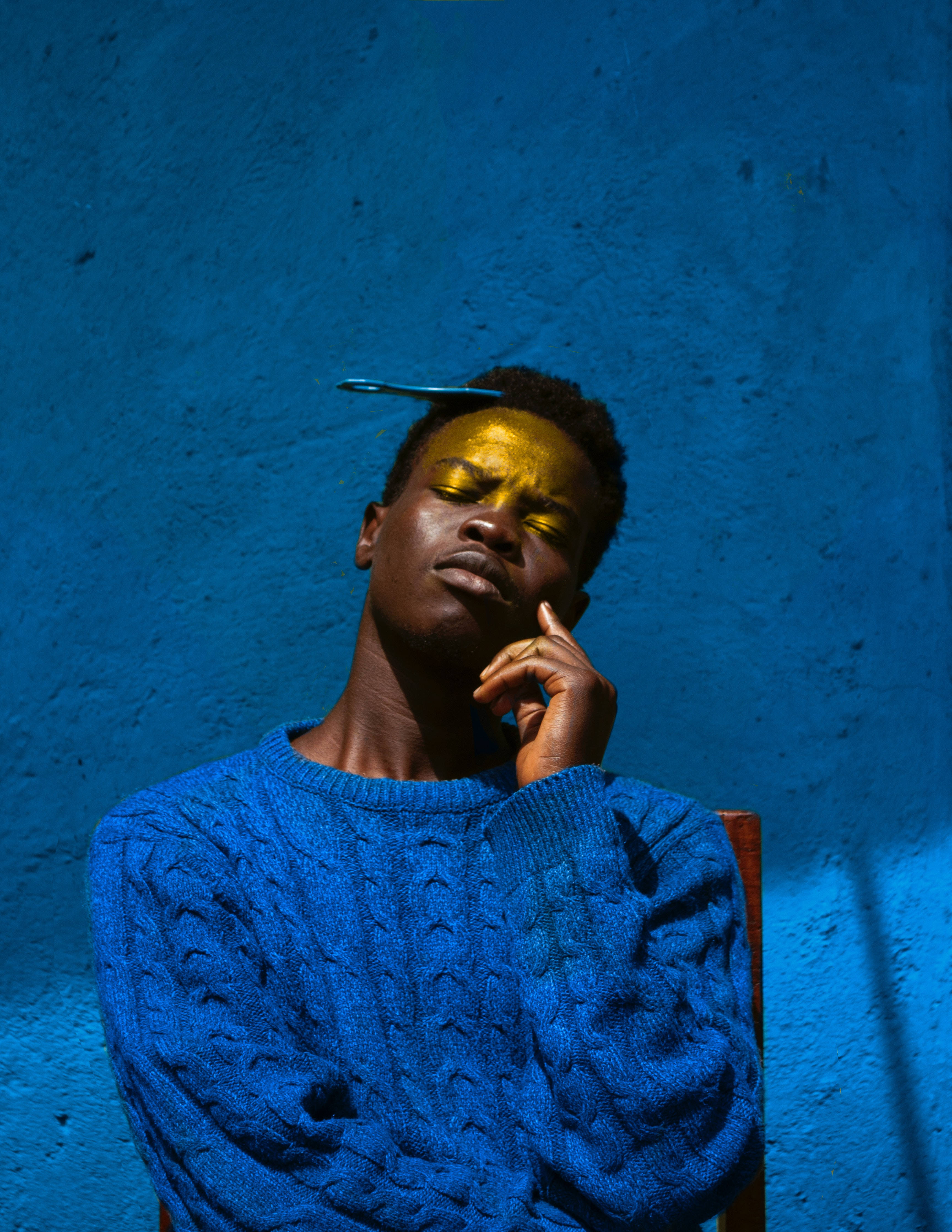 blue knitted sweater, golden face paint, textured blue wall, 4K Phone Wallpaper
