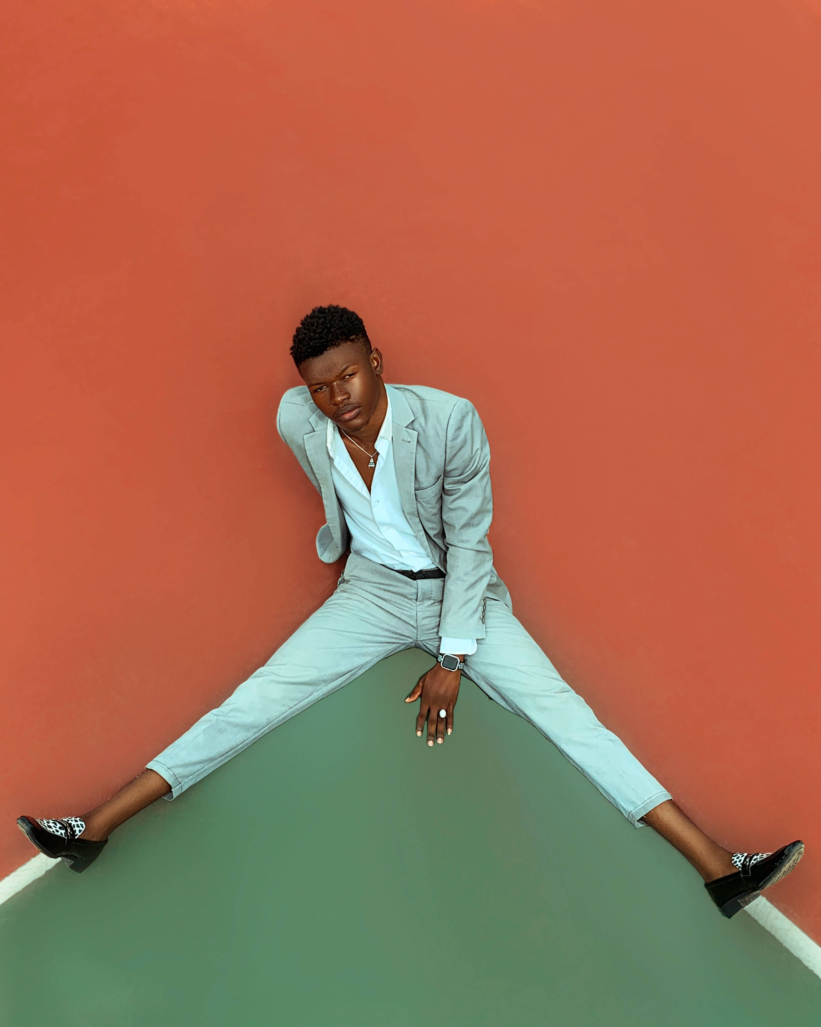 light gray suit, bold orange wall, green floor, 2K Phone Wallpaper