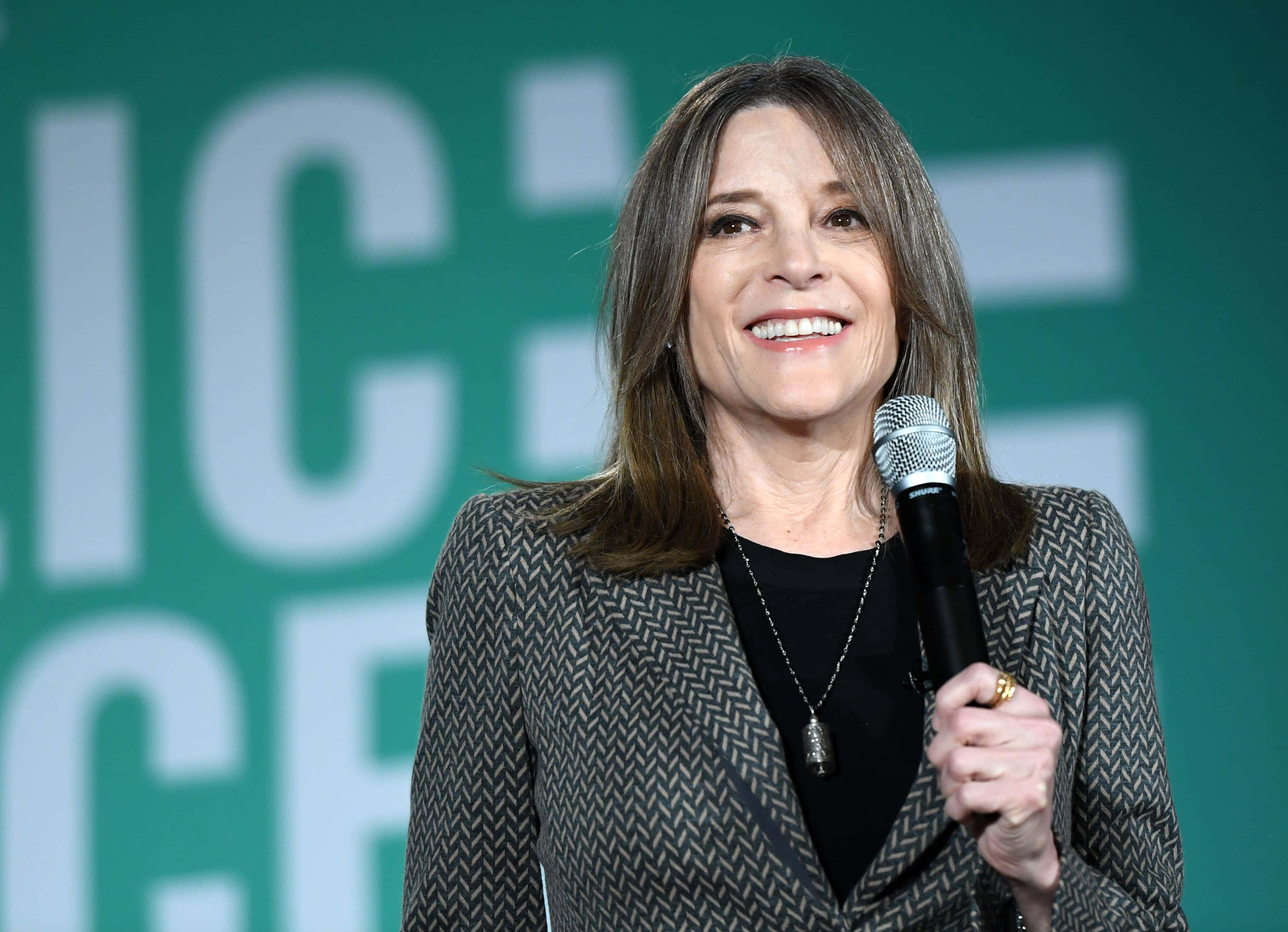 Marianne Williamson, microphone, green backdrop, 2K Desktop Wallpaper