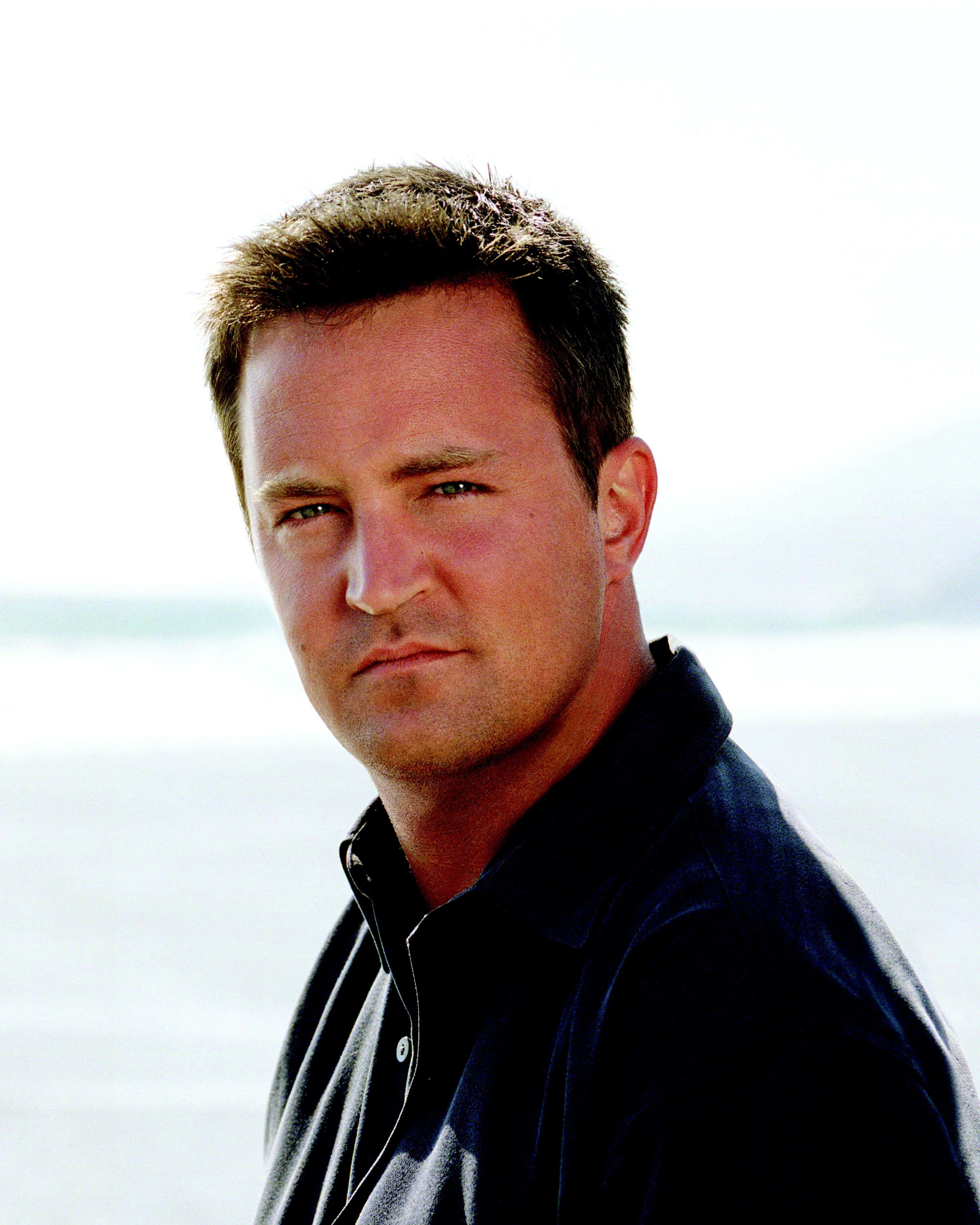 Matthew Perry, dark polo shirt, bright blurred water and sky background, 4K Phone Wallpaper