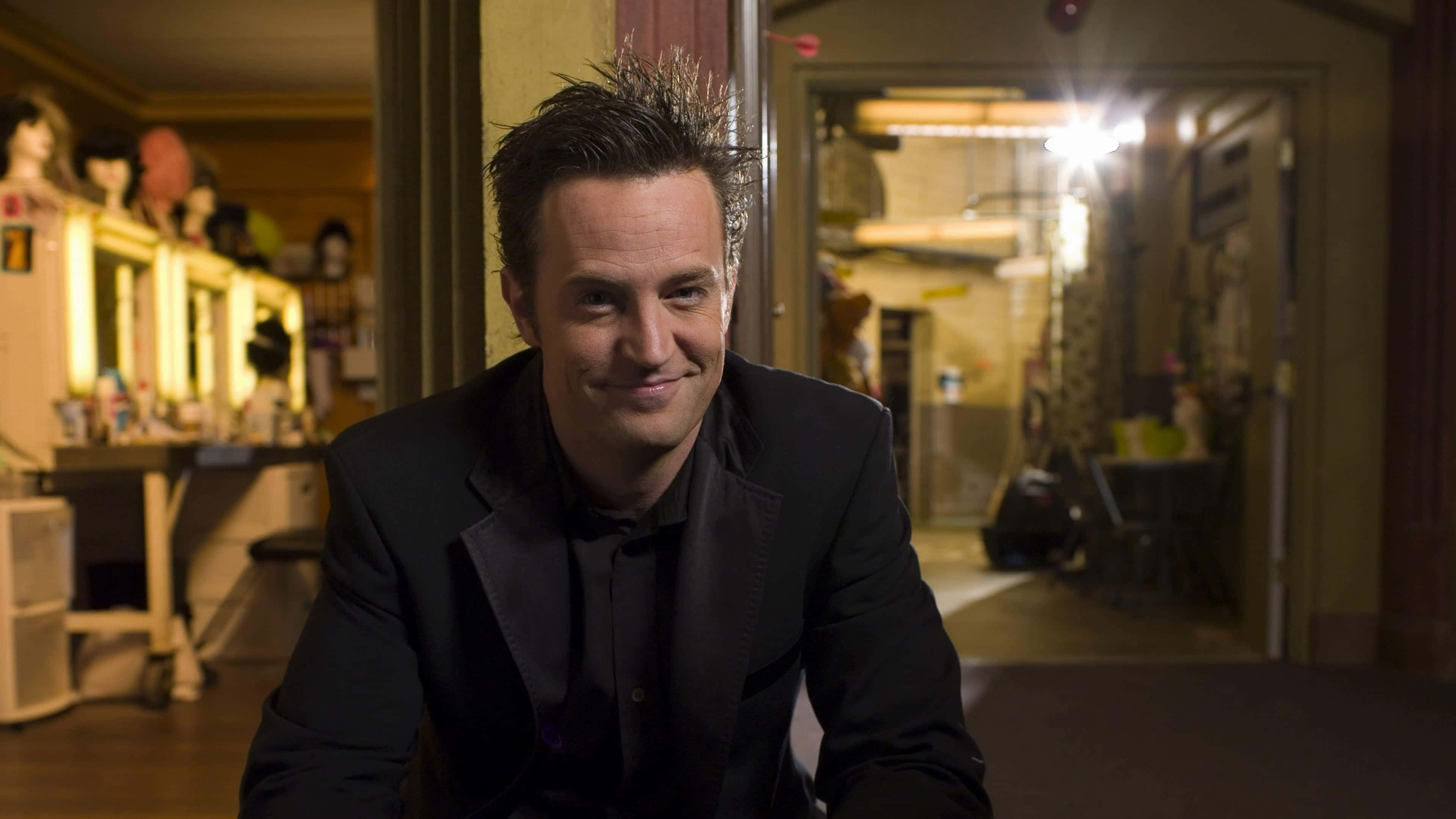 Matthew Perry, black suit, dimly lit backstage area, 4K Desktop Wallpaper