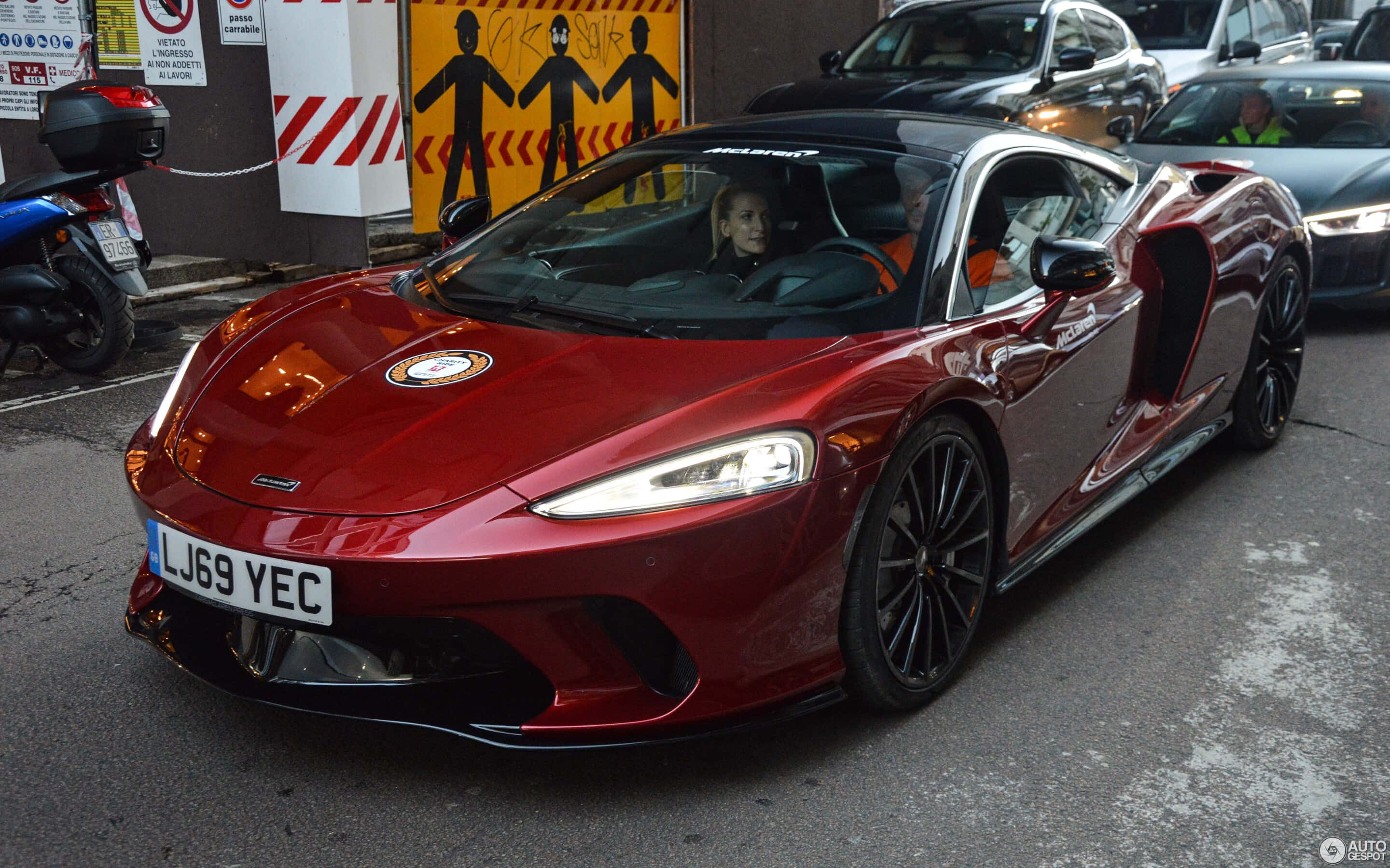 McLaren GT, glossy red, busy urban street, 2K Desktop Wallpaper