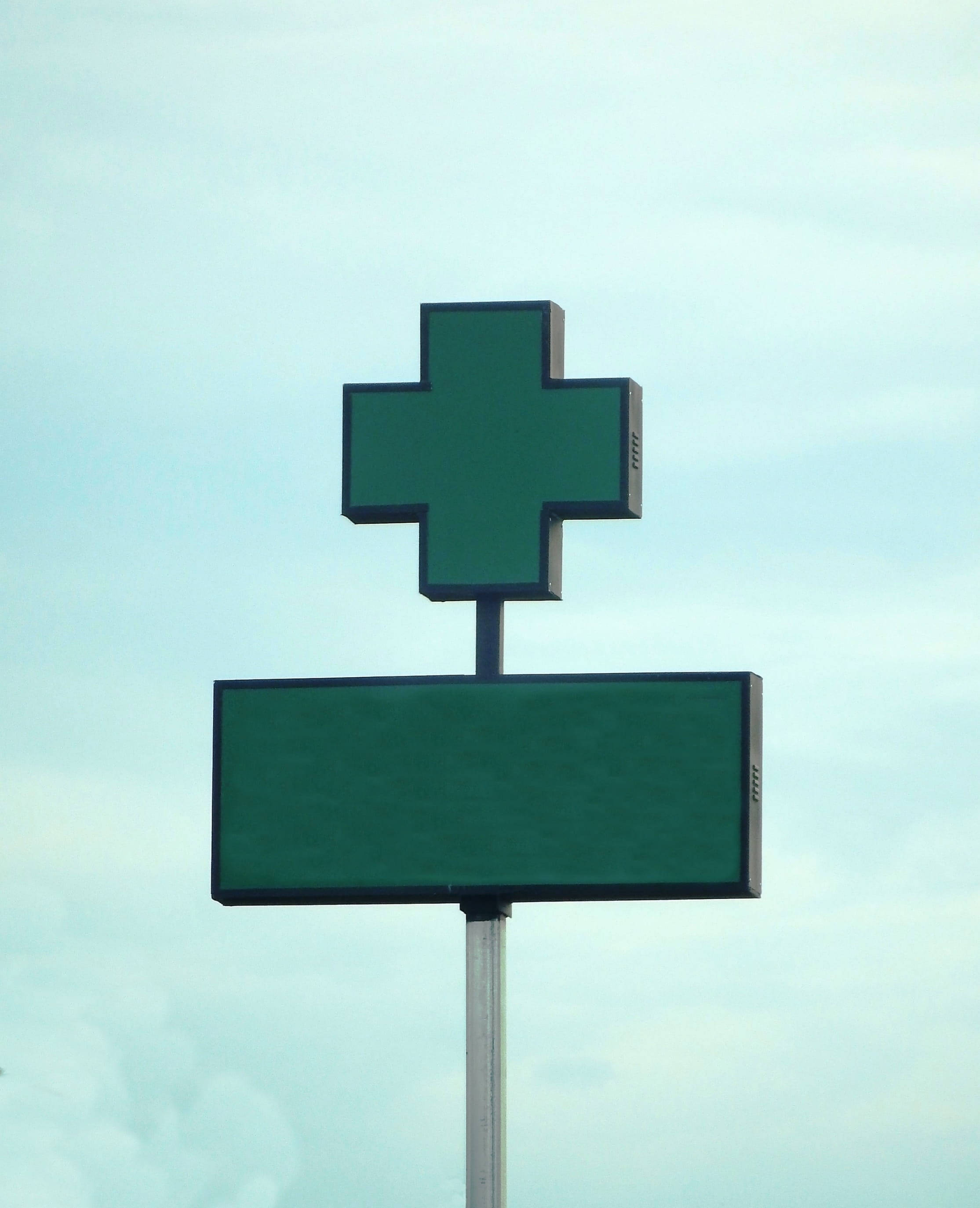 green pharmacy cross sign, soft blue sky, scattered clouds, 2K Phone Wallpaper
