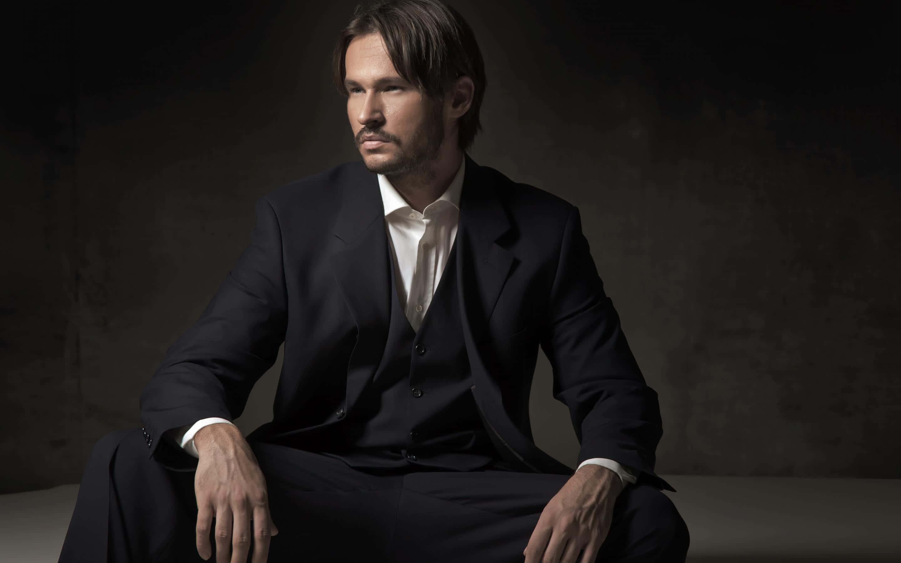 dark suit, textured wall, dramatic studio lighting, 2K Desktop Wallpaper
