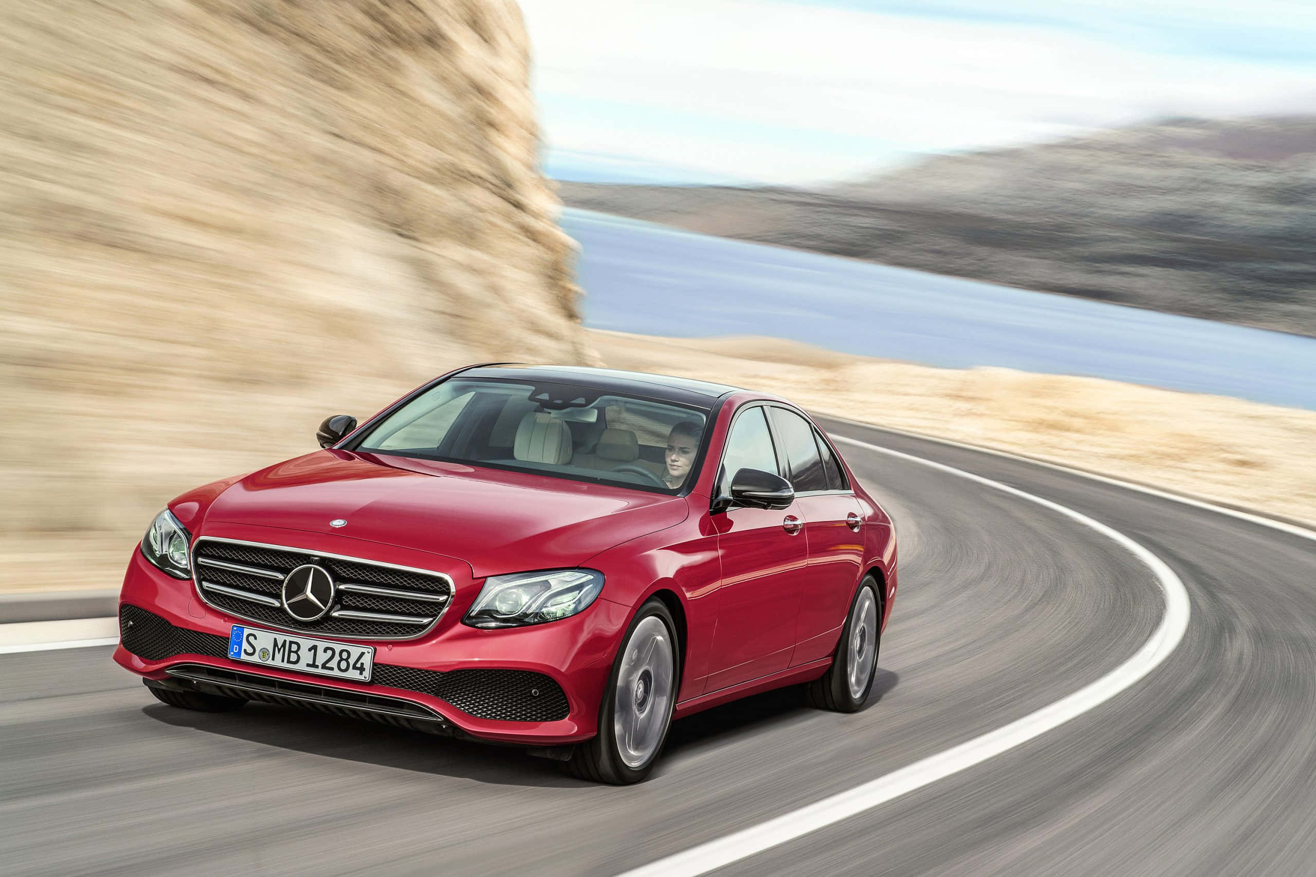 Mercedes Benz Clase E, vibrant red, winding coastal road, 2K Desktop Wallpaper