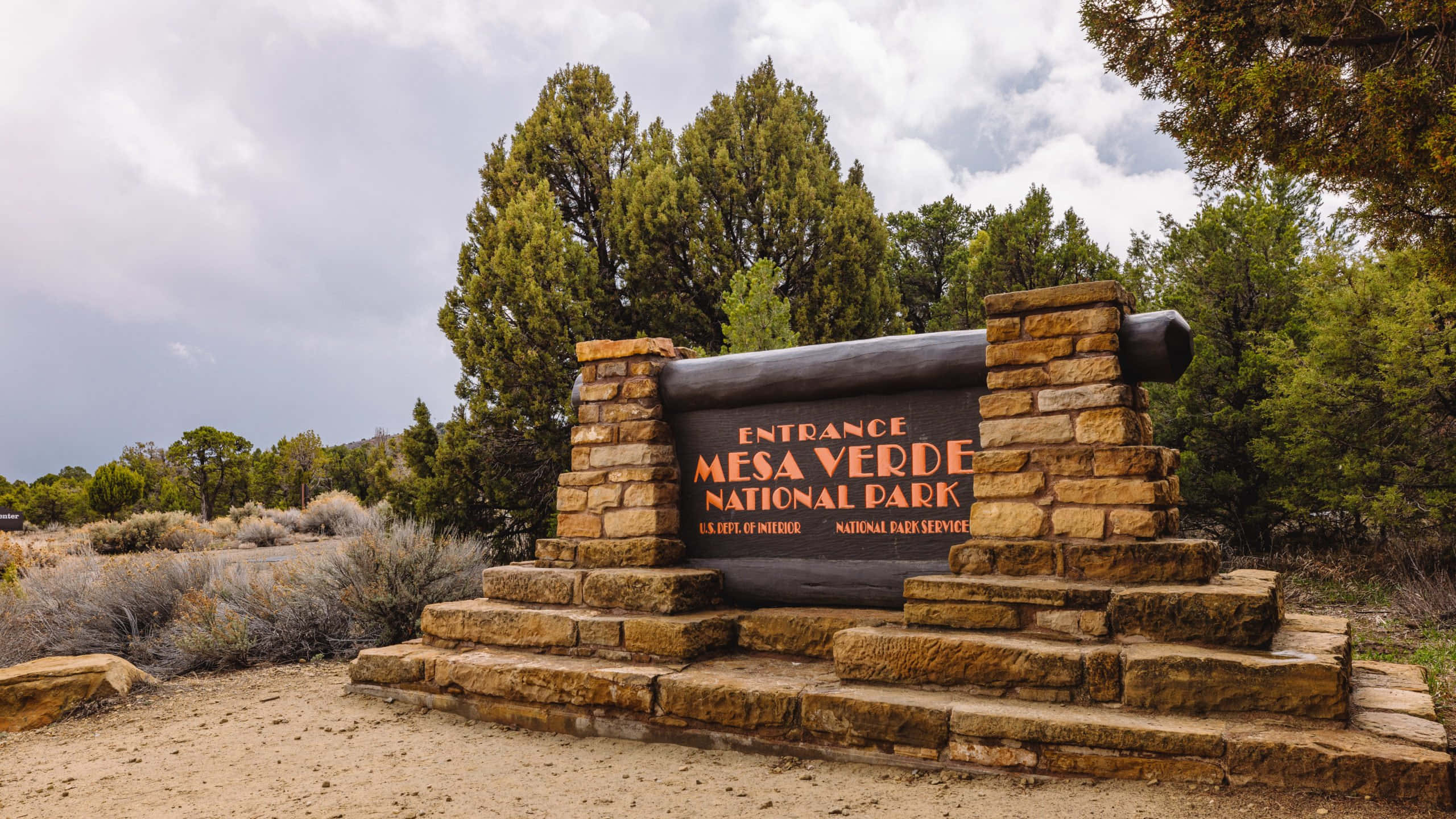 Mesa Verde National Park, stone archway entrance sign, cloudy sky, 2K Desktop Wallpaper