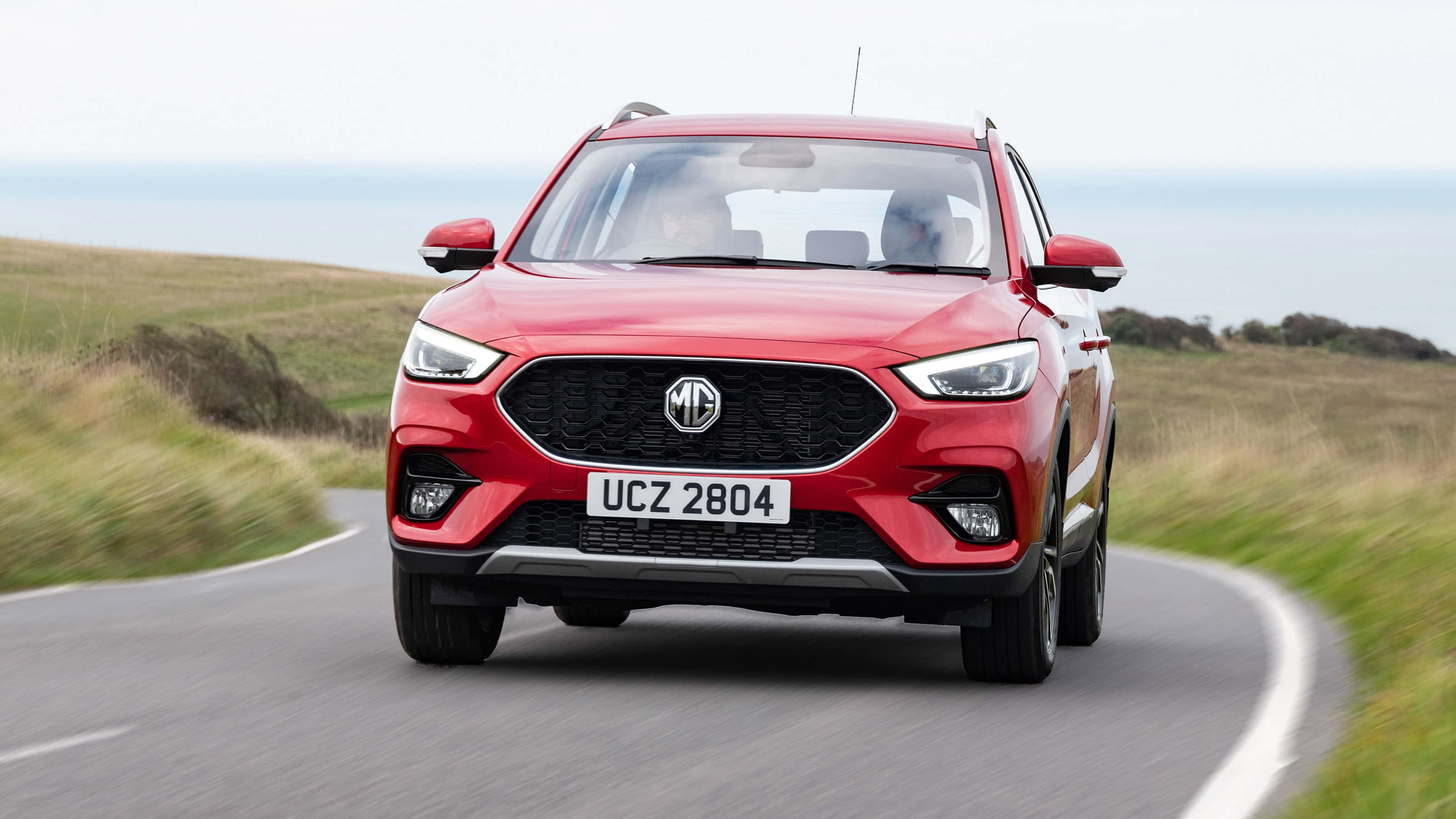 MG Zs, vibrant red, winding coastal road, 2K Desktop Wallpaper