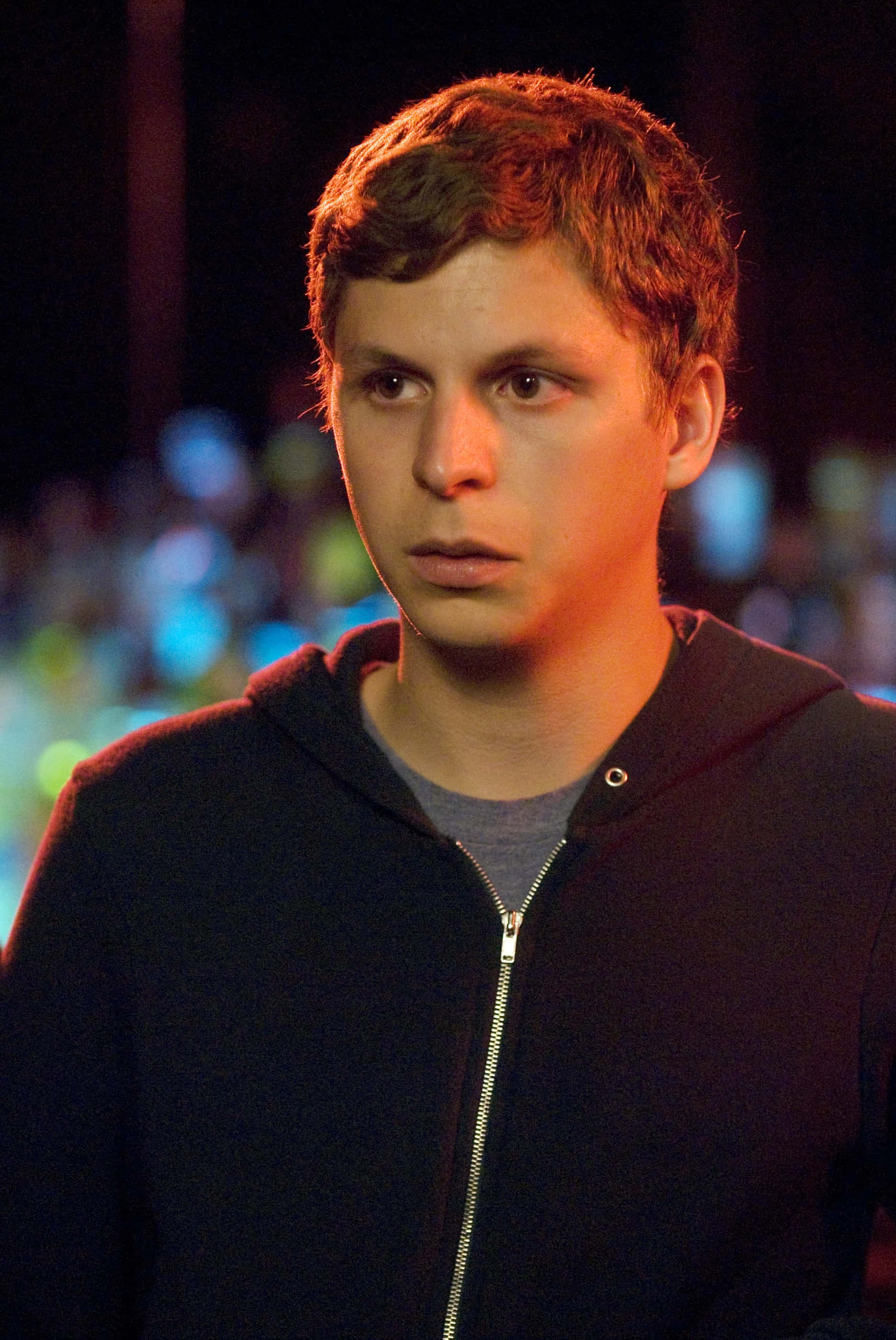 Michael Cera, dark hoodie, blurred night backdrop, 2K Phone Wallpaper