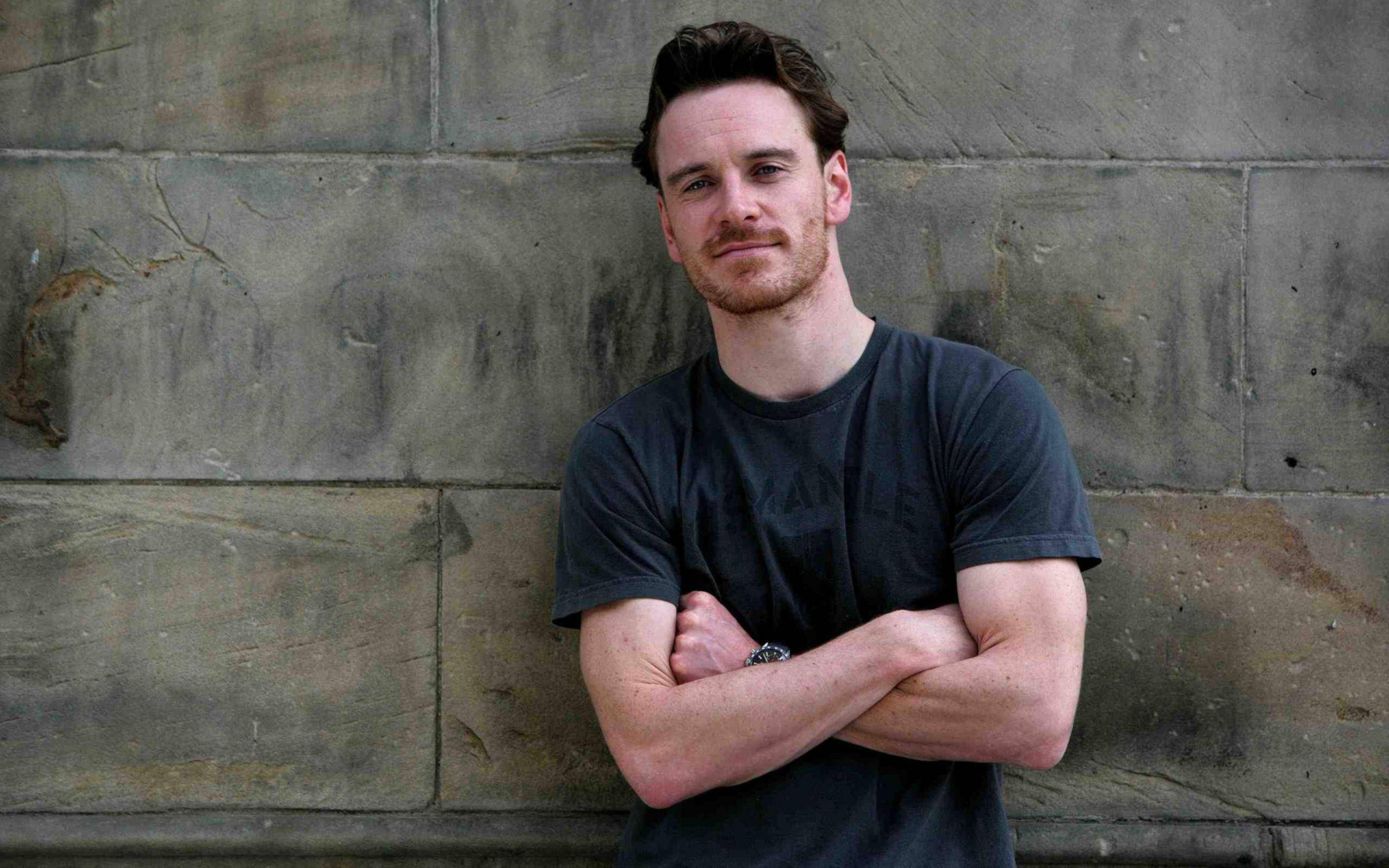 Michael Fassbender, weathered stone wall, candid portrait, 2K Desktop Wallpaper